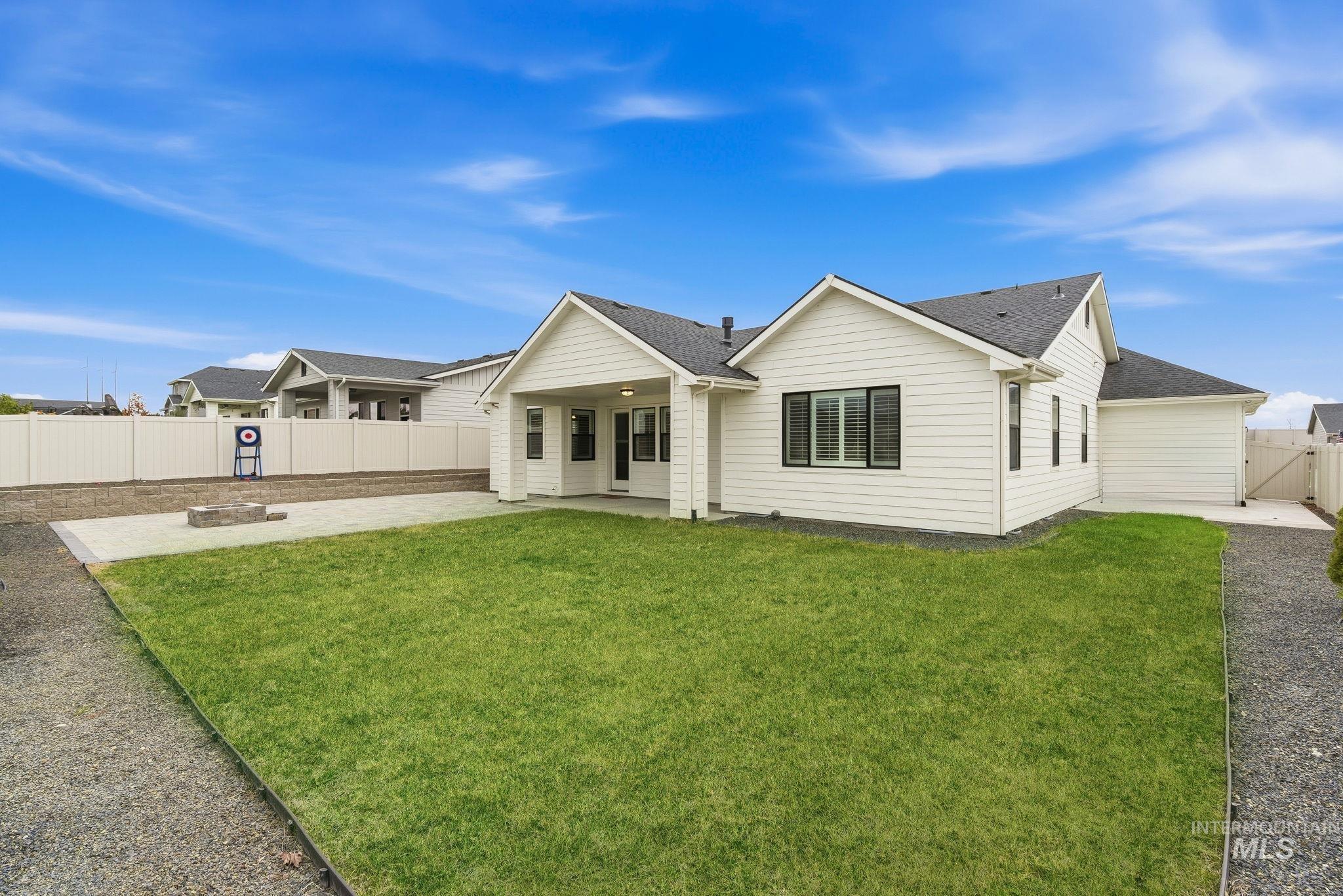 Rear view of house featuring a patio area, a fenced backyard, and roof with shingles