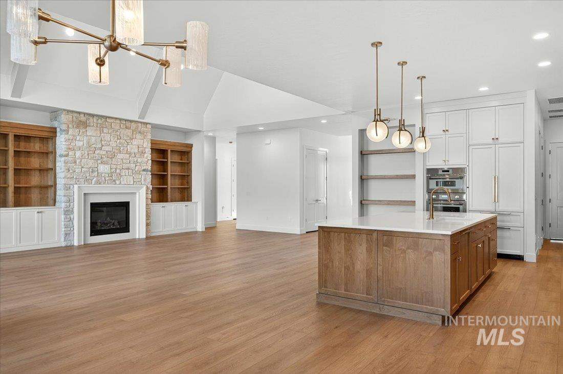 Kitchen with brown cabinetry, open floor plan, white cabinetry, lofted ceiling, and recessed lighting