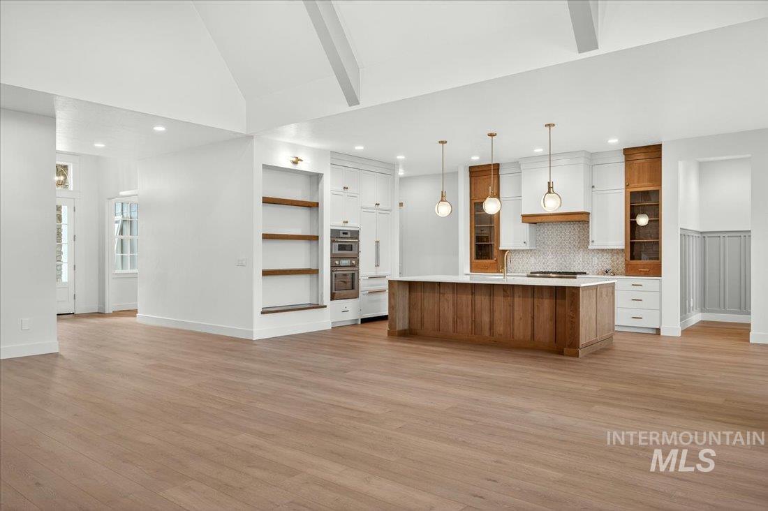 Kitchen with brown cabinets, light countertops, light wood finished floors, a spacious island, and open floor plan