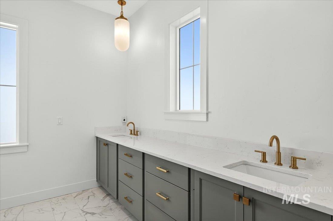 Bathroom featuring double vanity and light marble finish flooring