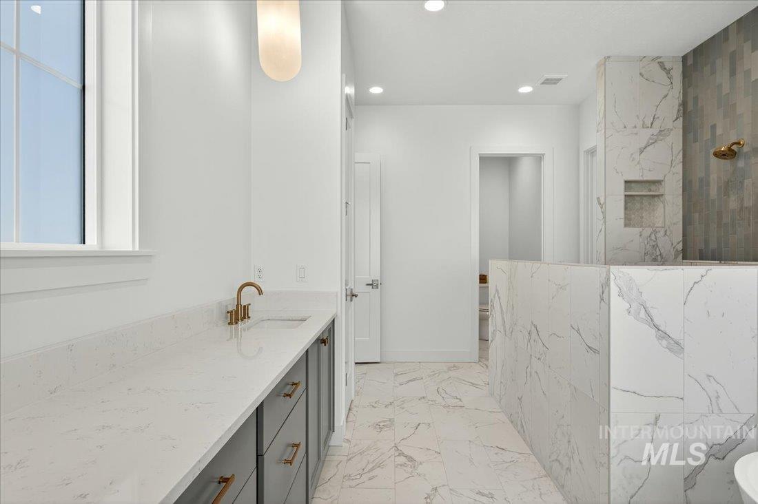 Bathroom with a marble finish shower, light marble finish floors, vanity, and recessed lighting