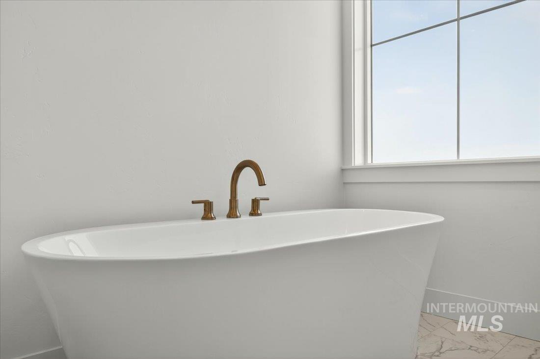 Full bath with a freestanding tub and baseboards