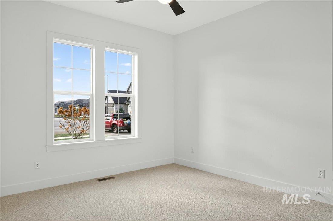 Carpeted spare room featuring baseboards and a ceiling fan