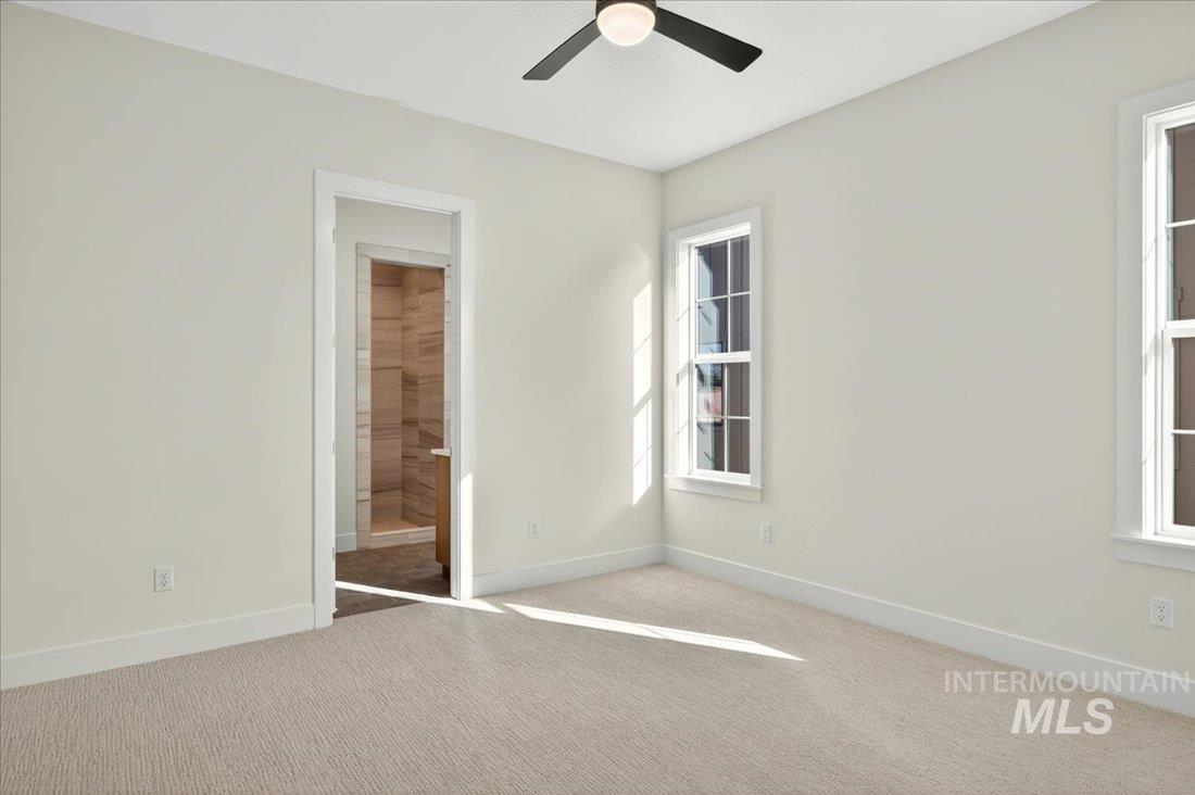 Unfurnished bedroom with carpet floors, ensuite bathroom, and ceiling fan