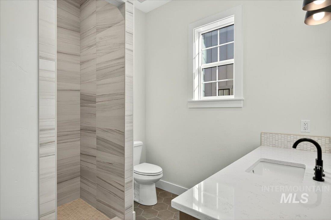 Bathroom featuring vanity, dark tile patterned flooring, and a tile shower