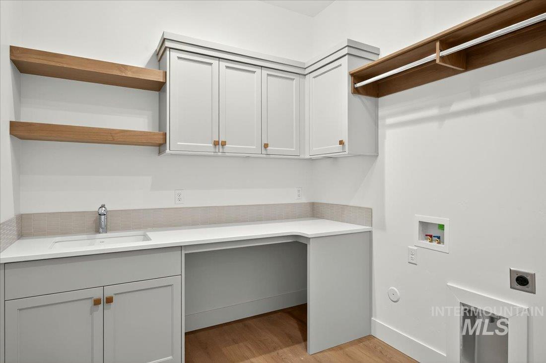 Washroom featuring light wood finished floors, washer hookup, electric dryer hookup, and cabinet space