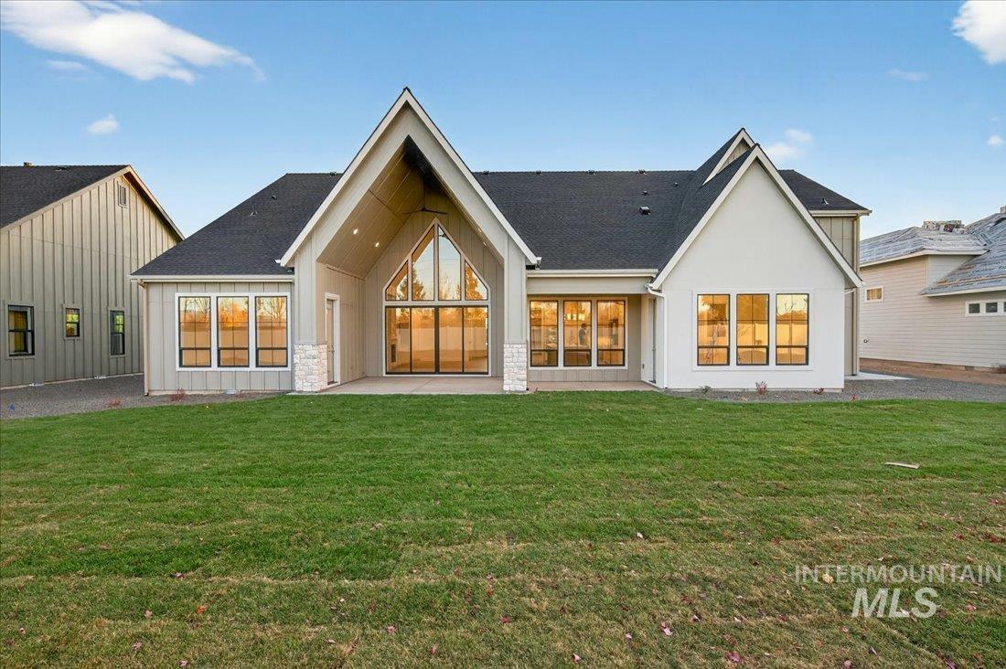 Back of property with a patio, a yard, board and batten siding, and a shingled roof