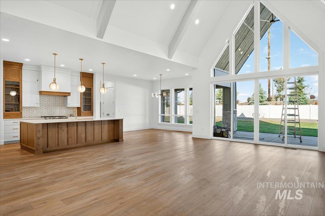 Unfurnished living room featuring high vaulted ceiling, beam ceiling, a chandelier, light wood-style floors, and recessed lighting