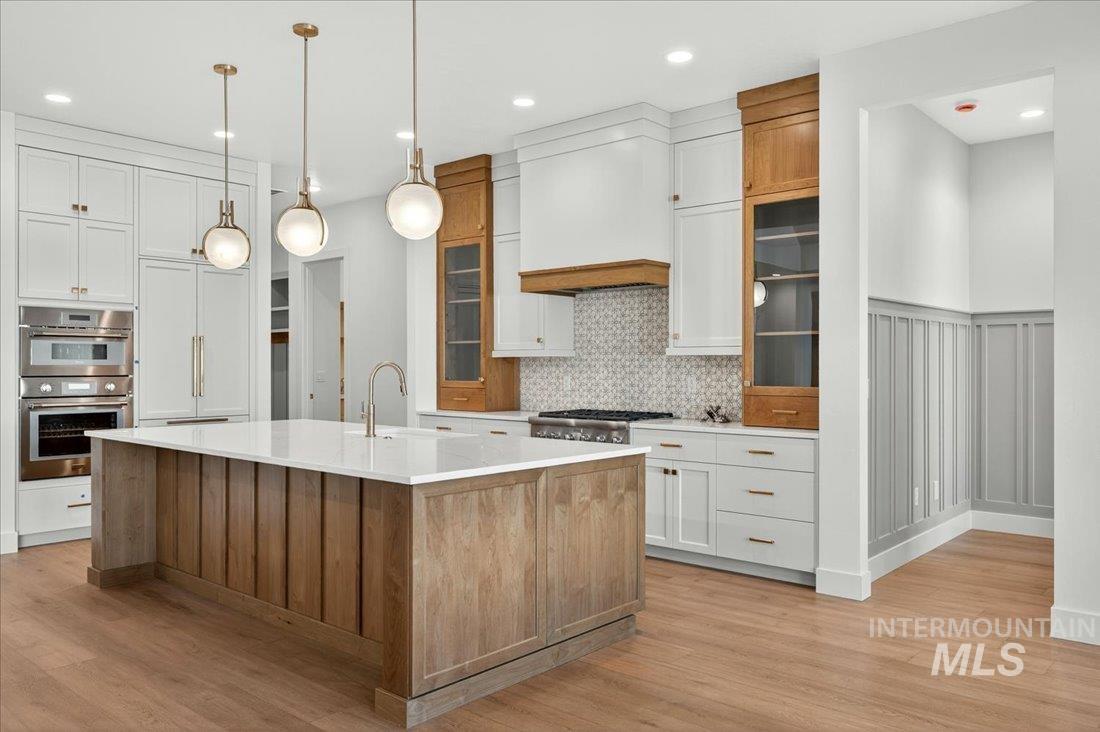 Kitchen featuring brown cabinetry, white cabinetry, a spacious island, stainless steel double oven, and recessed lighting