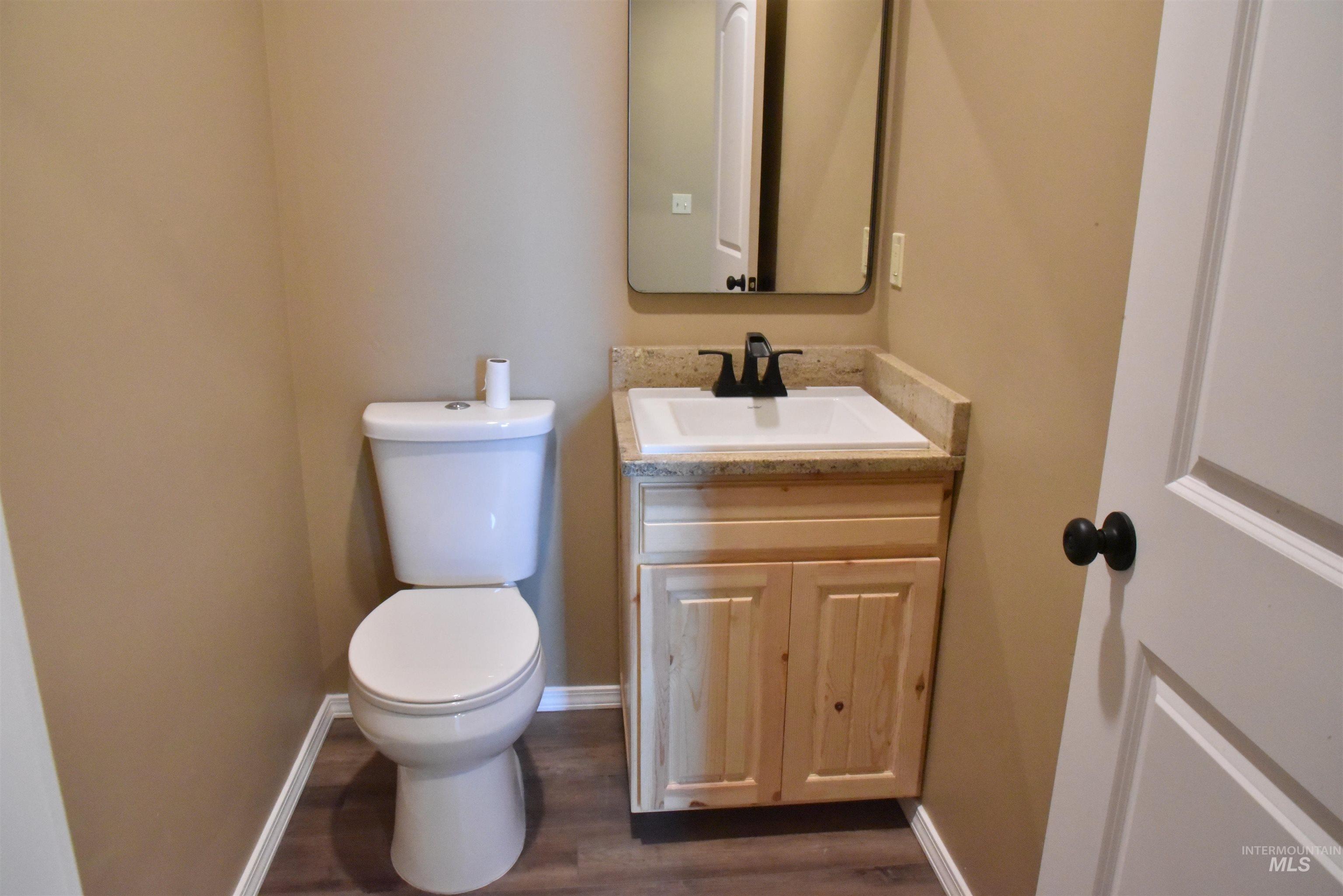 Half bath with vanity and dark wood-style flooring