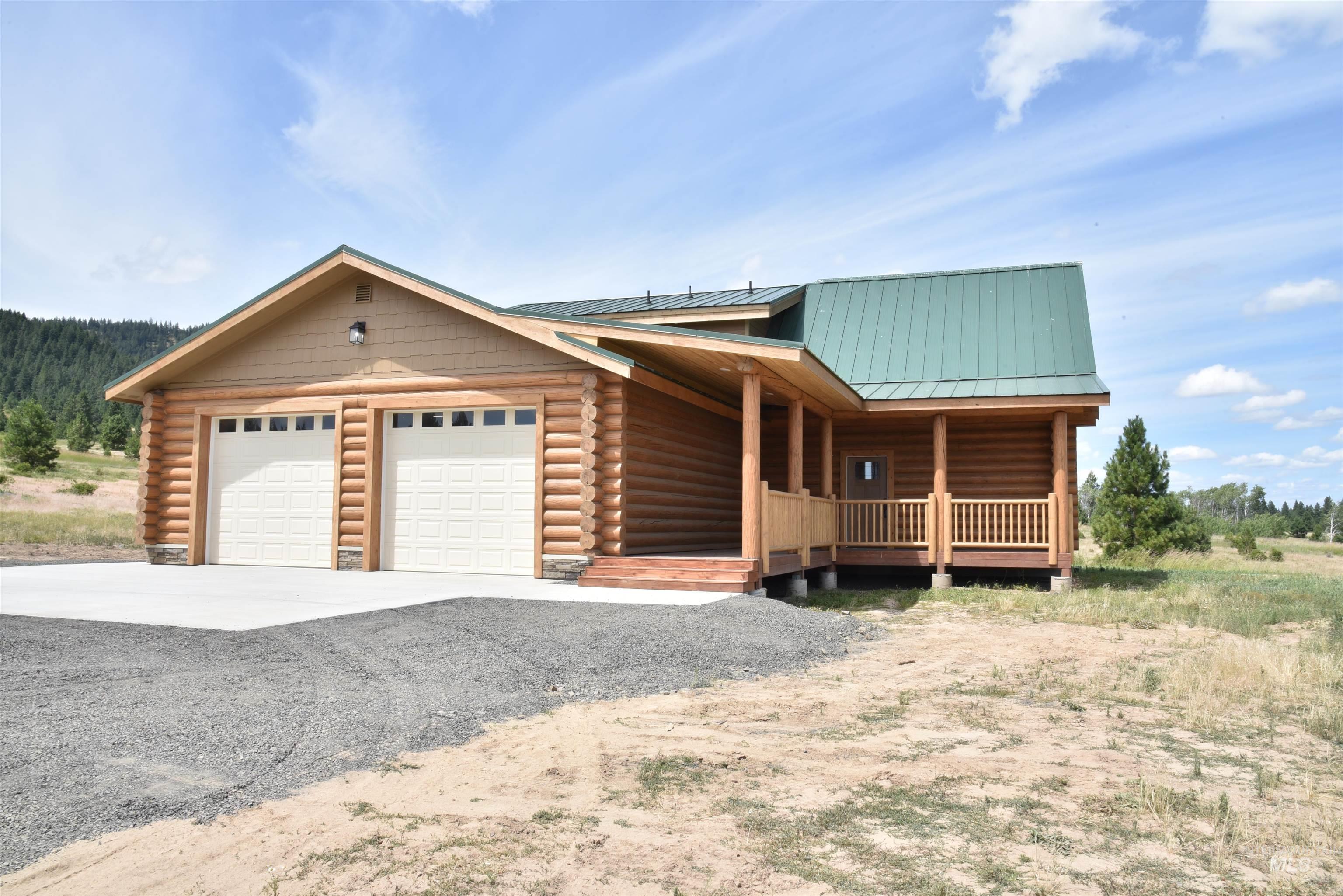 Log home with log siding, an attached garage, and driveway