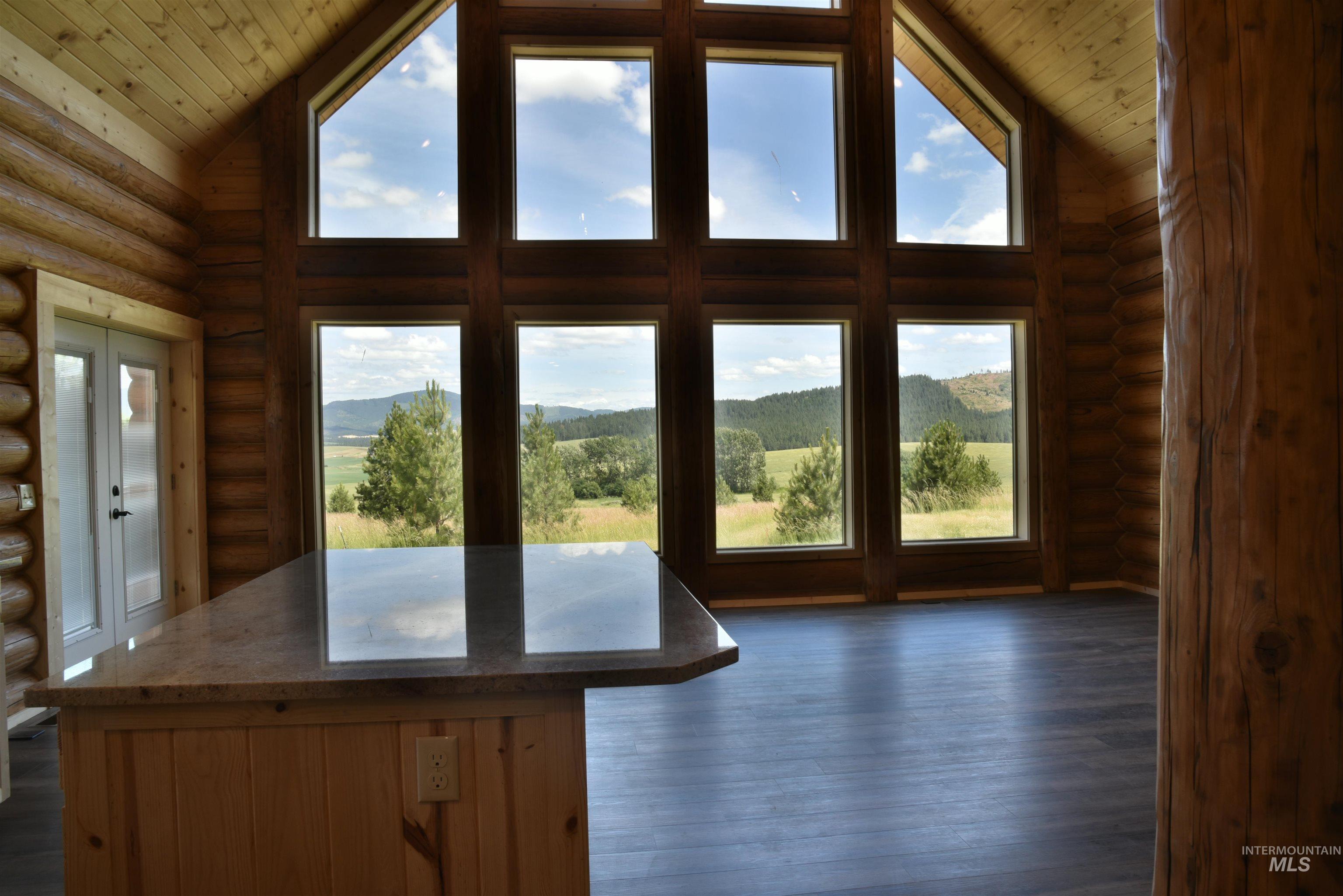 Entryway with log walls, a mountain view, high vaulted ceiling, wood ceiling, and wood finished floors