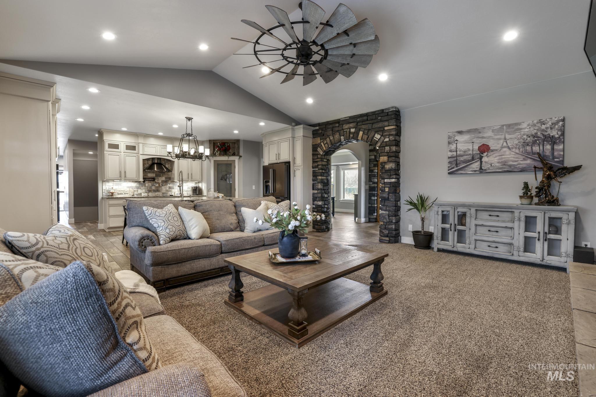Living room featuring vaulted ceiling, arched walkways, a chandelier, recessed lighting, and light carpet