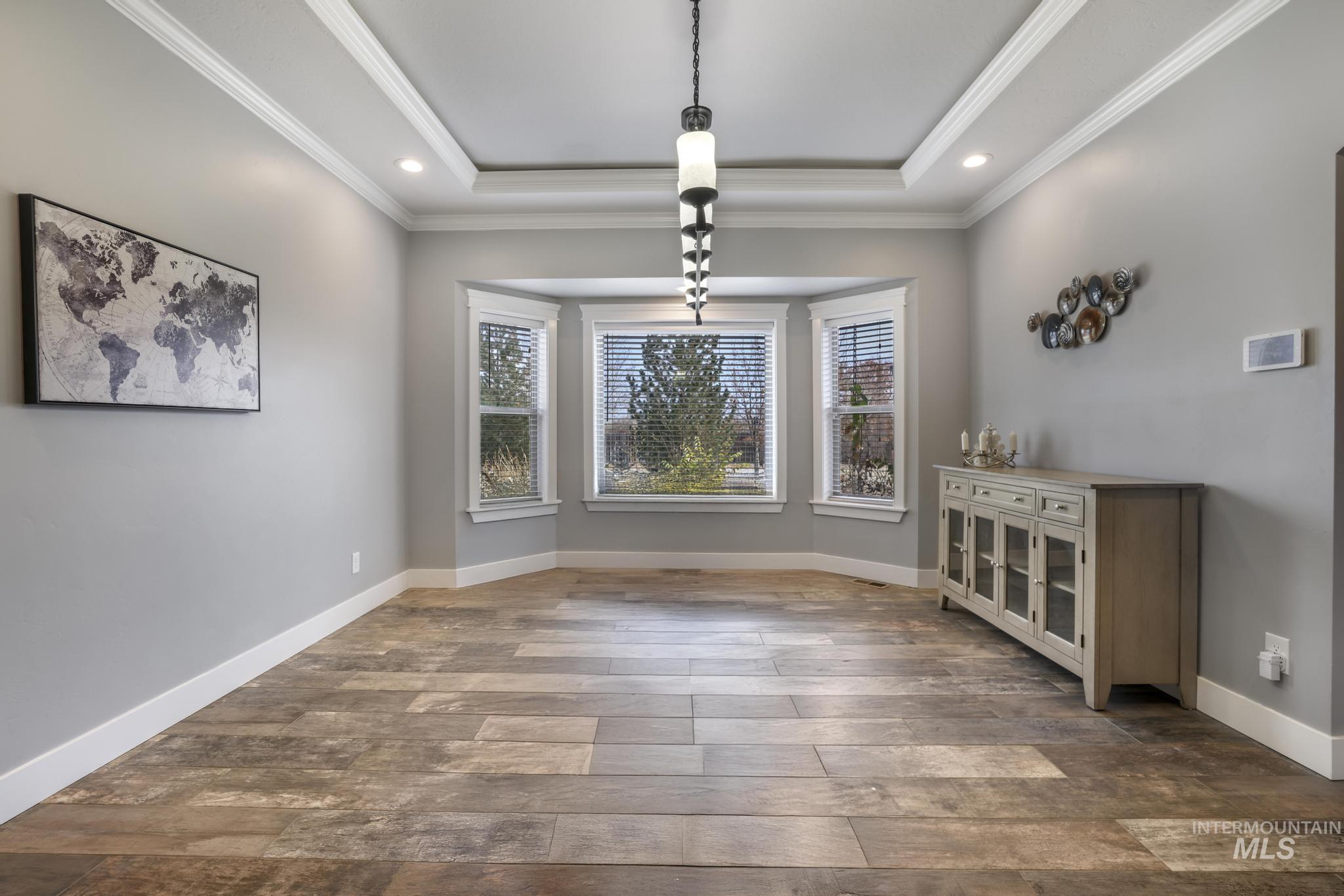 Unfurnished dining area featuring recessed lighting, dark wood finished floors, a tray ceiling, and crown molding