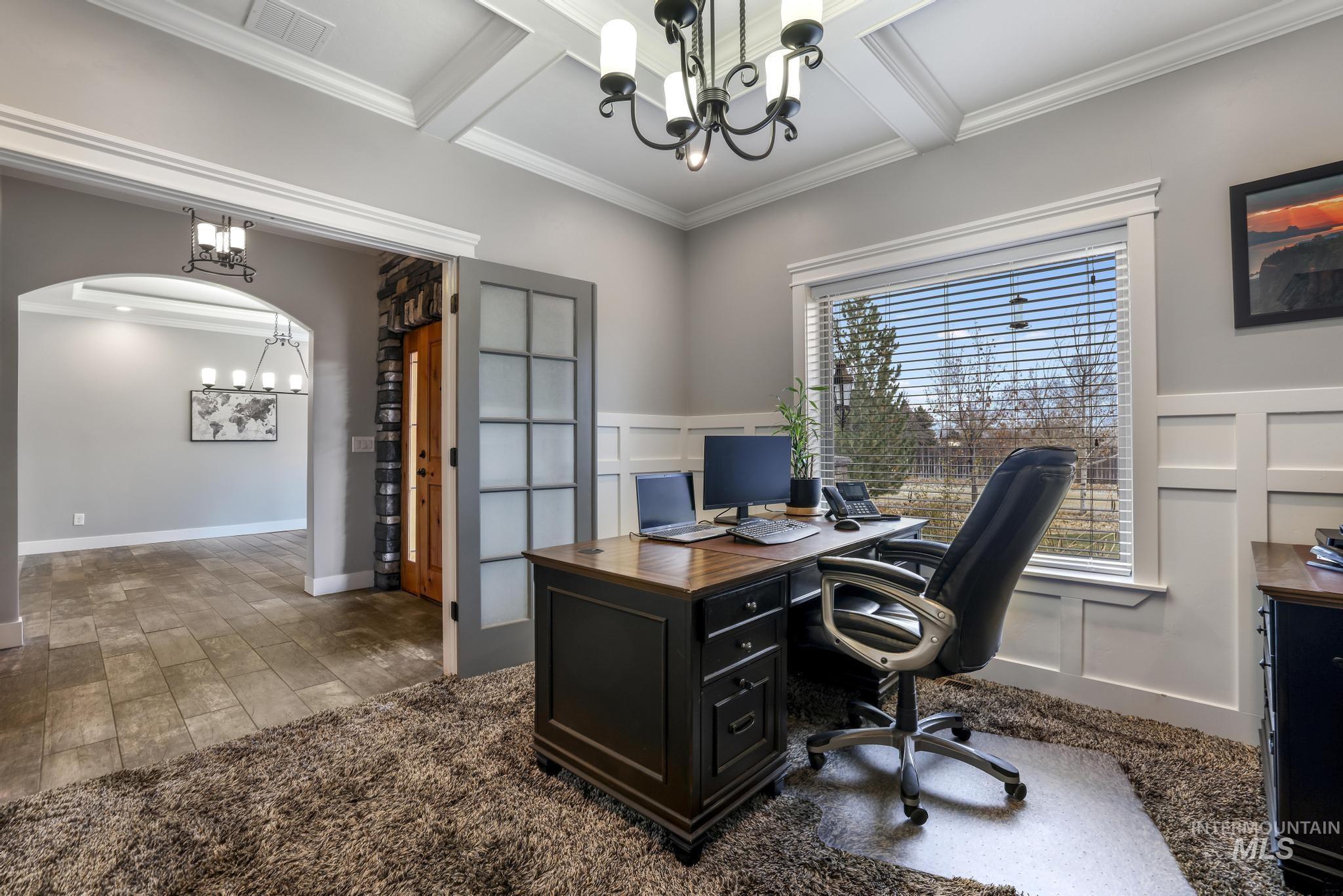Home office with a chandelier, crown molding, arched walkways, carpet, and beam ceiling