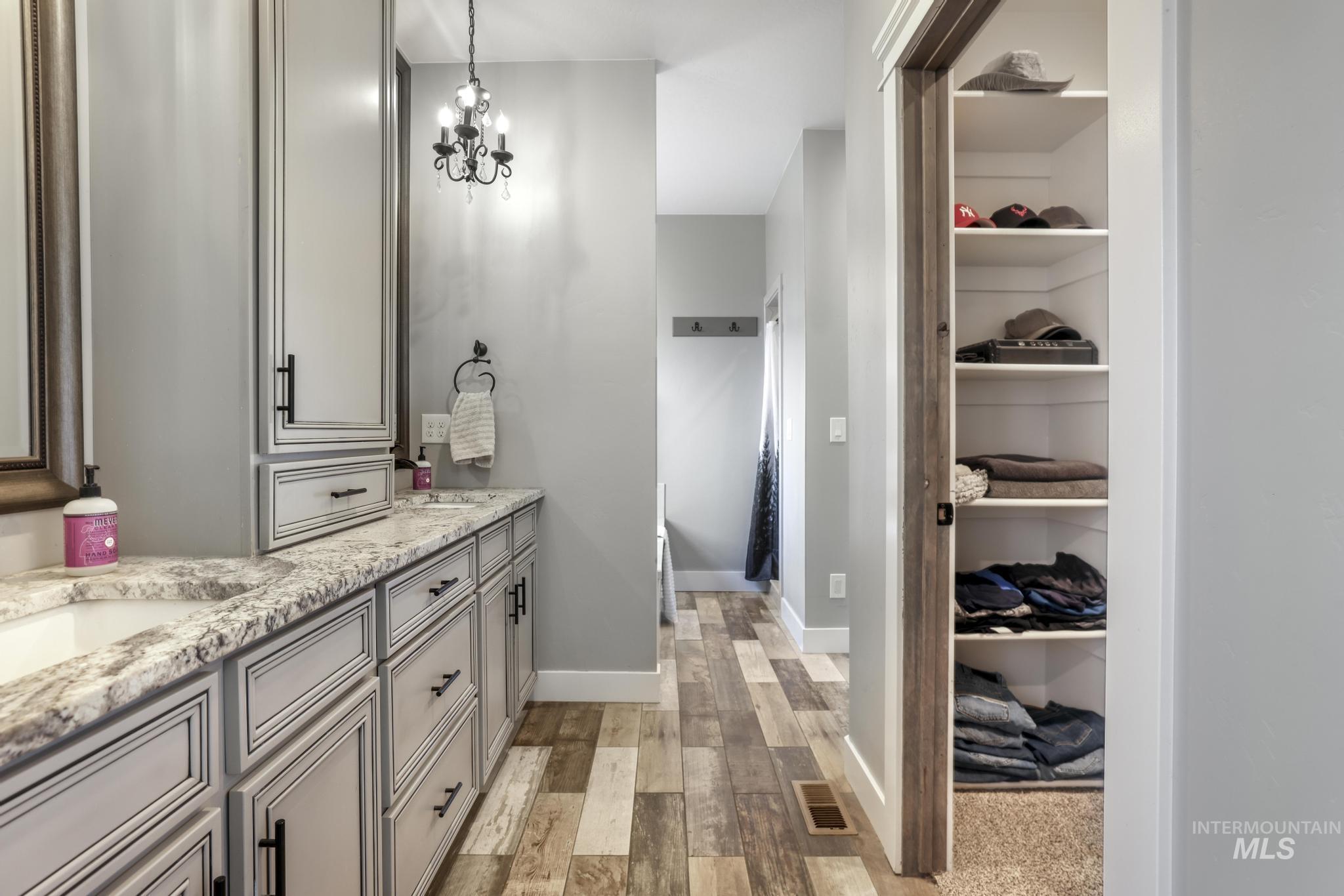 Full bath with light wood-type flooring, double vanity, and a chandelier