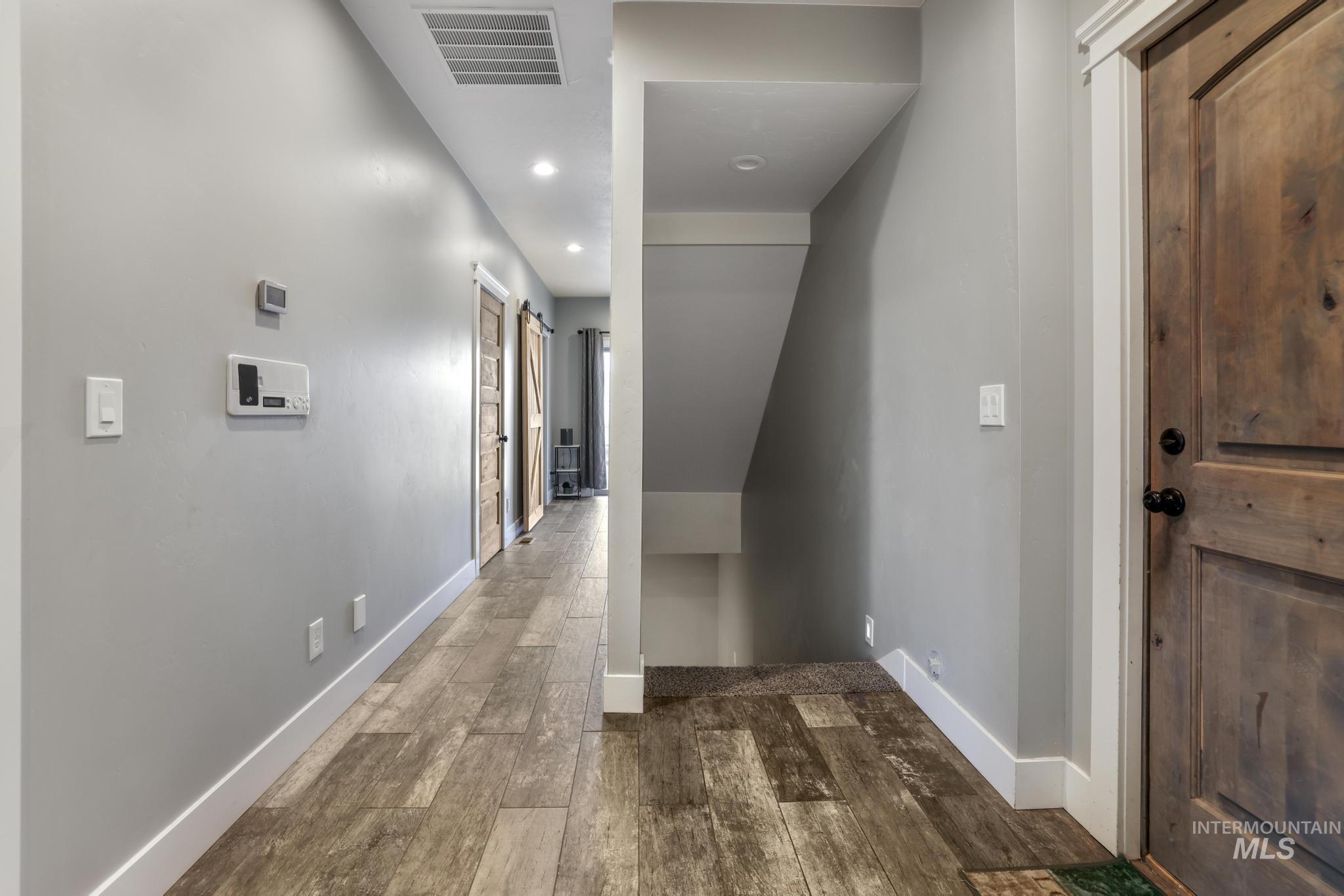 Hall featuring dark wood-style floors, recessed lighting, and a barn door