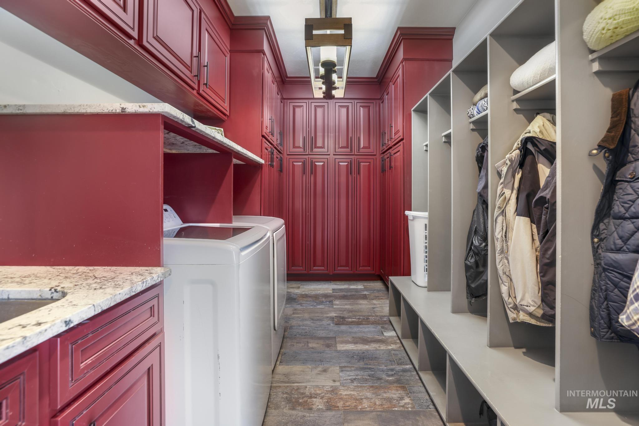 Washroom featuring dark wood finished floors, washer and dryer, crown molding, and cabinet space