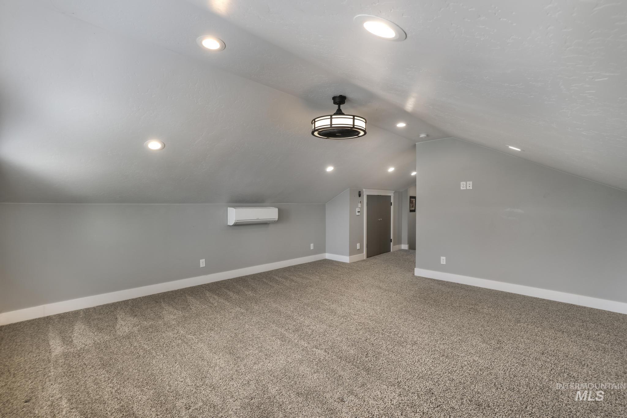 Bonus room featuring vaulted ceiling, light colored carpet, recessed lighting, and an AC wall unit