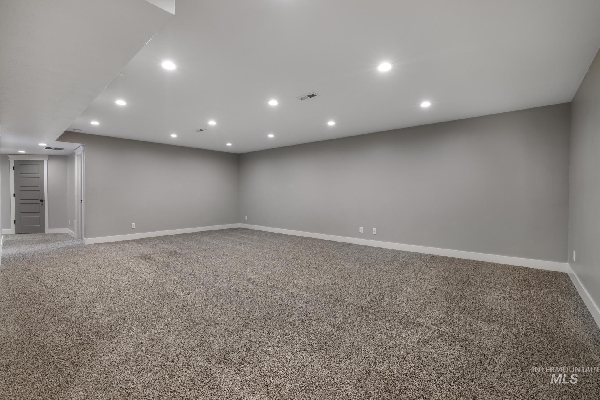 Empty room with light carpet and recessed lighting