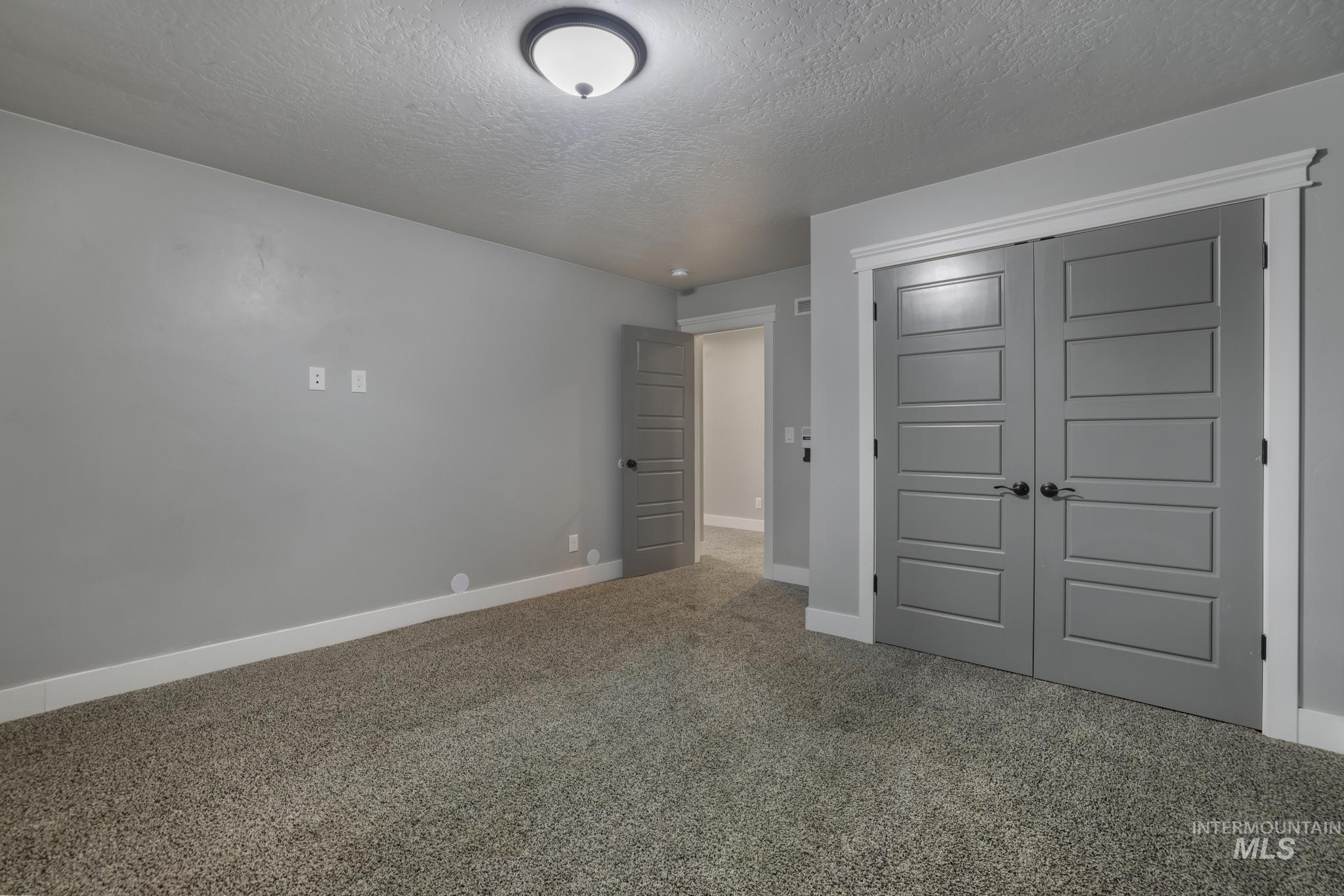 Unfurnished bedroom with a textured ceiling, carpet flooring, and a closet