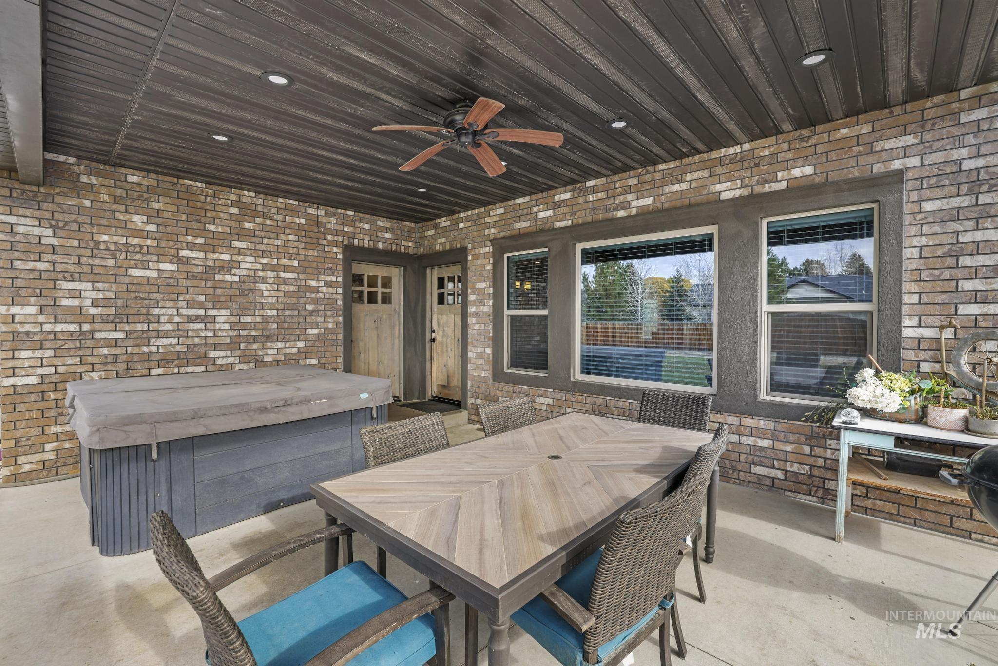 View of patio / terrace featuring outdoor dining area, ceiling fan, and a hot tub