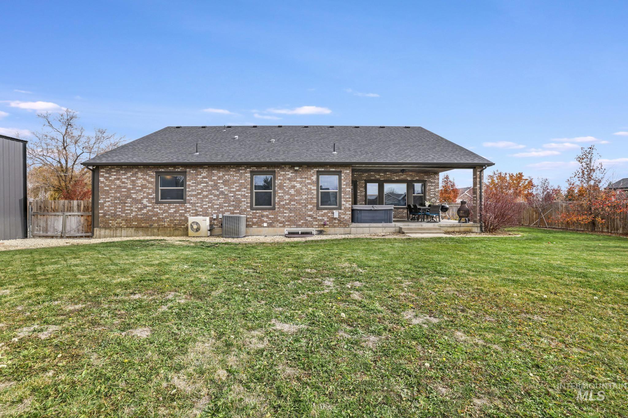 Rear view of house featuring a patio, brick siding, and roof with shingles