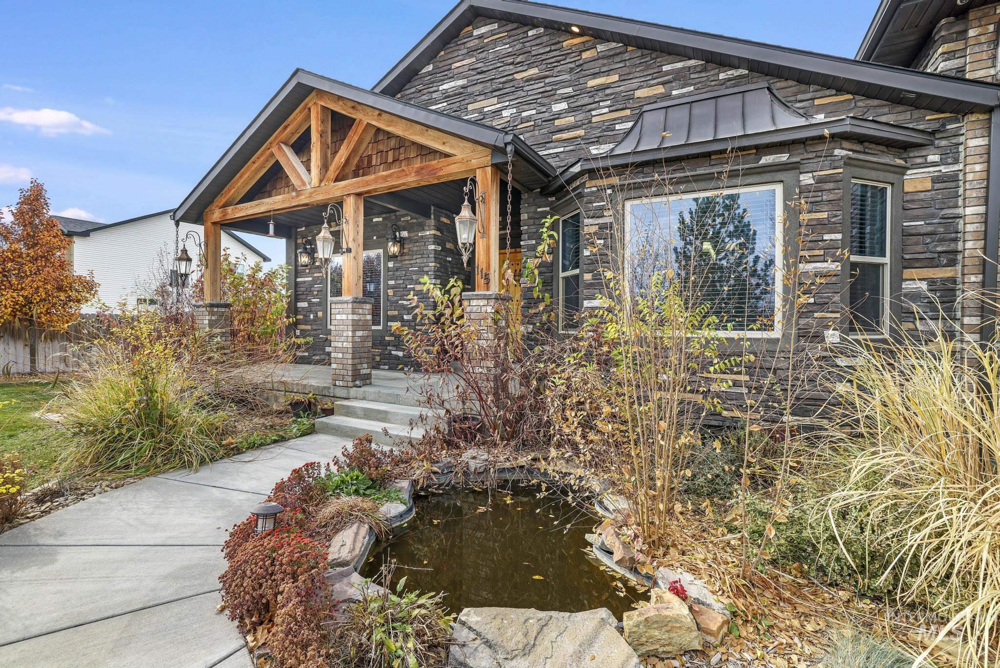 View of front of house featuring a standing seam roof, a metal roof, a garden pond, stone siding, and covered porch
