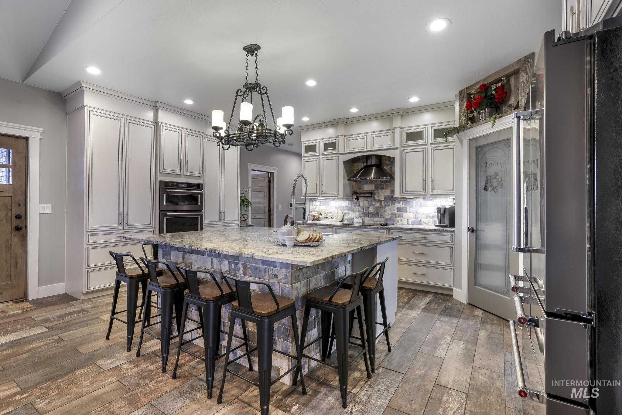 Kitchen featuring a breakfast bar, glass insert cabinets, black appliances, backsplash, and light stone counters