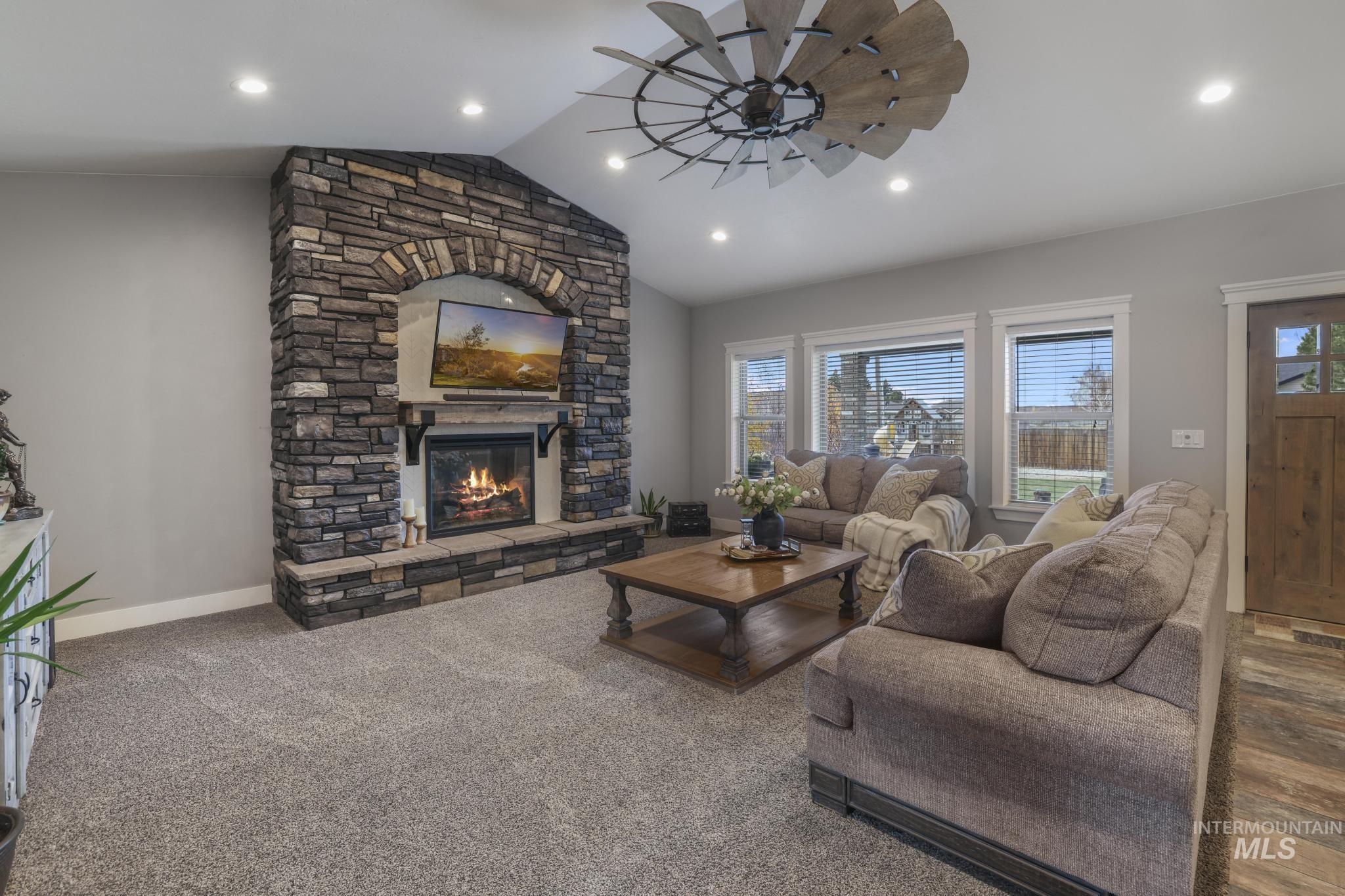 Living room featuring lofted ceiling, a fireplace, carpet floors, and recessed lighting