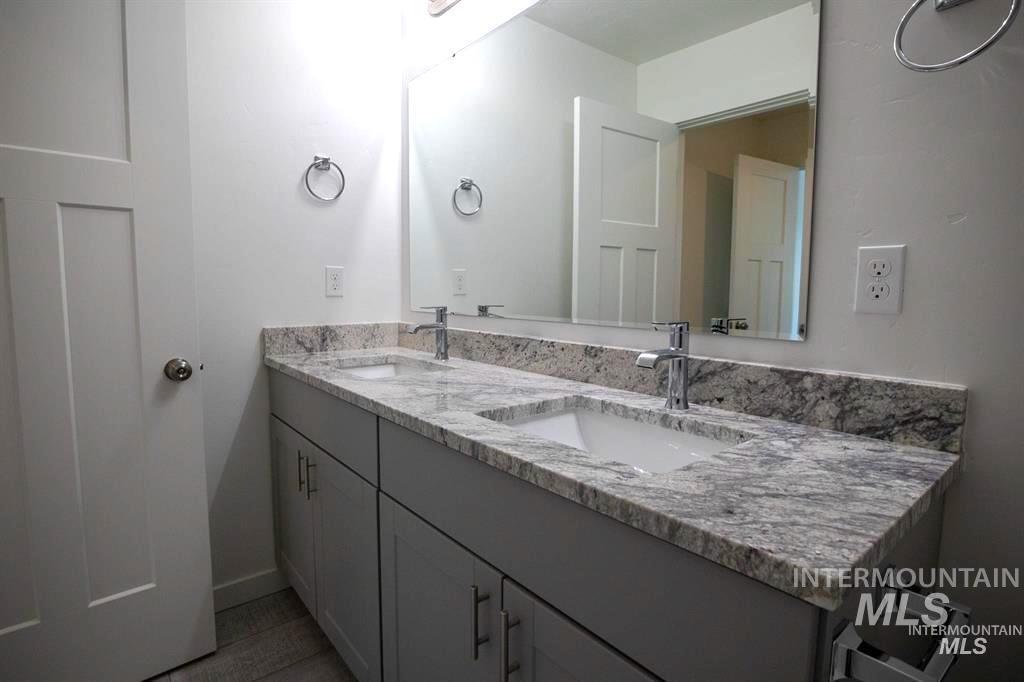 Full bathroom featuring double vanity and baseboards