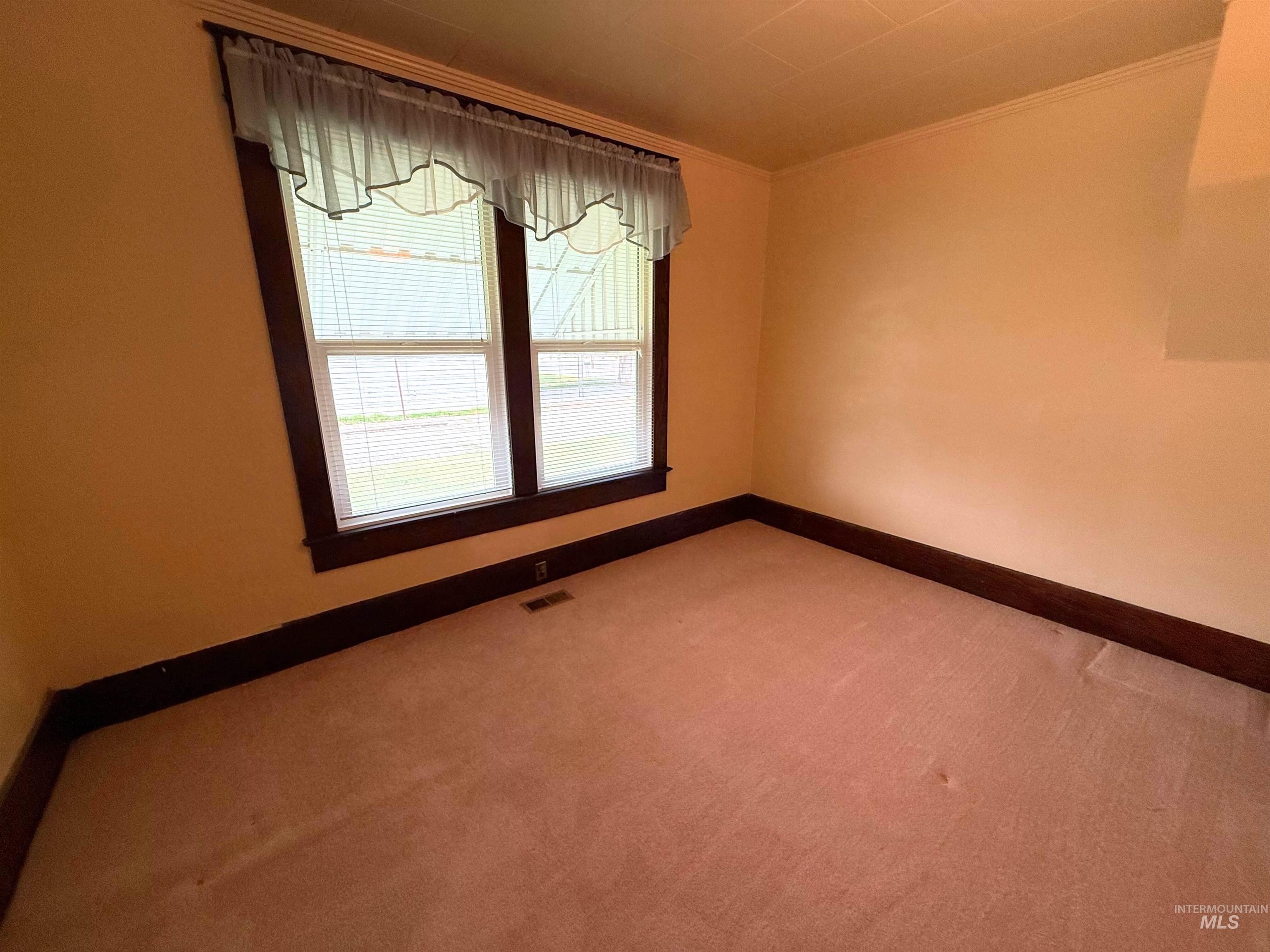 Carpeted spare room featuring ornamental molding and baseboards