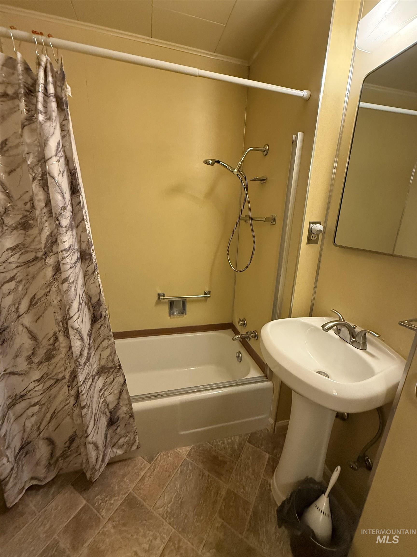 Full bath with shower / tub combo and dark stone finish flooring
