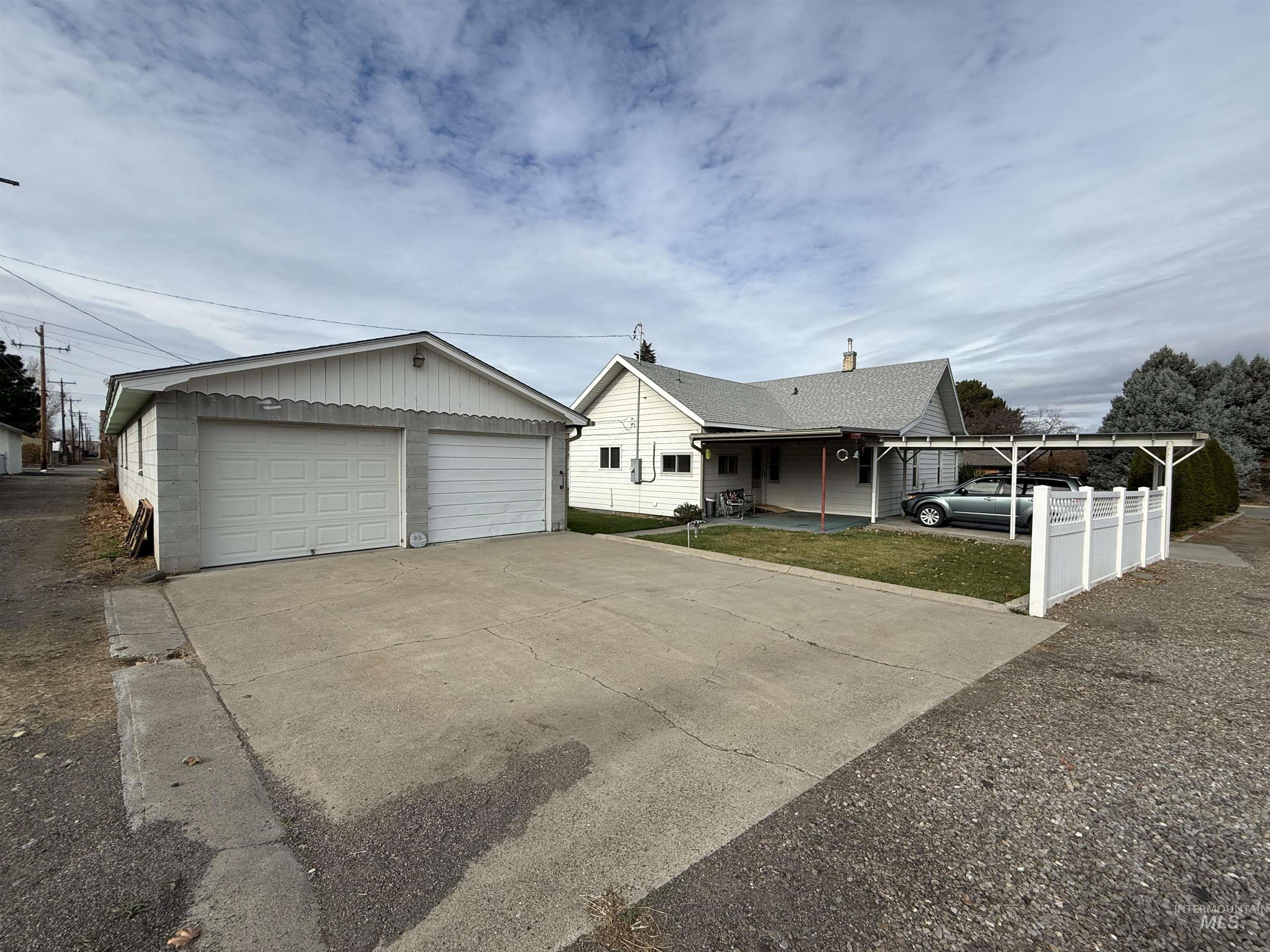 Ranch-style house with covered porch, a garage, a front yard, and an outbuilding
