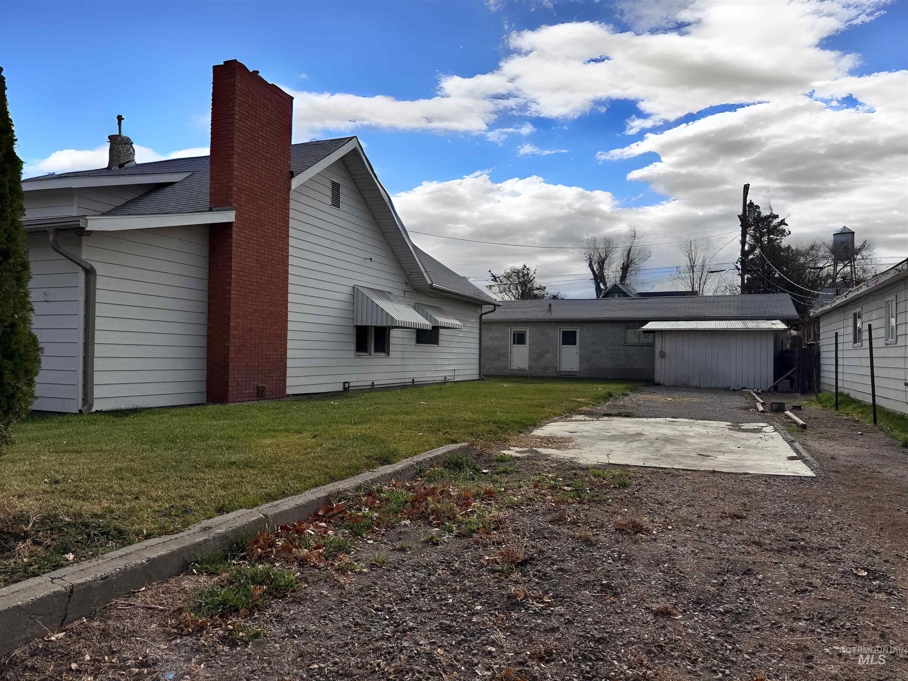 Rear view of house with a lawn, a chimney, and a patio