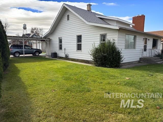 View of side of home with a chimney and a lawn