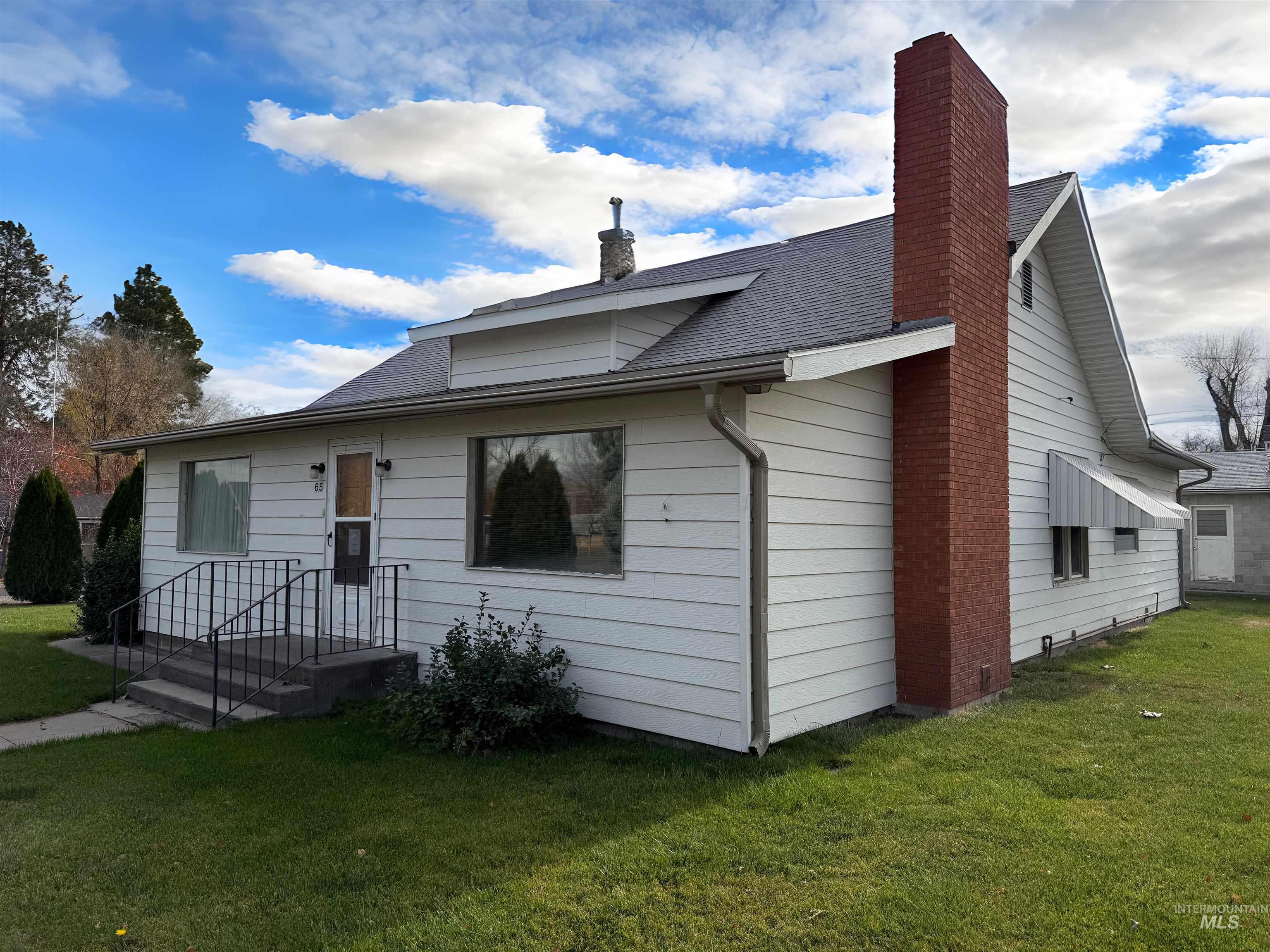 View of front of home featuring a chimney, a front yard, and roof with shingles