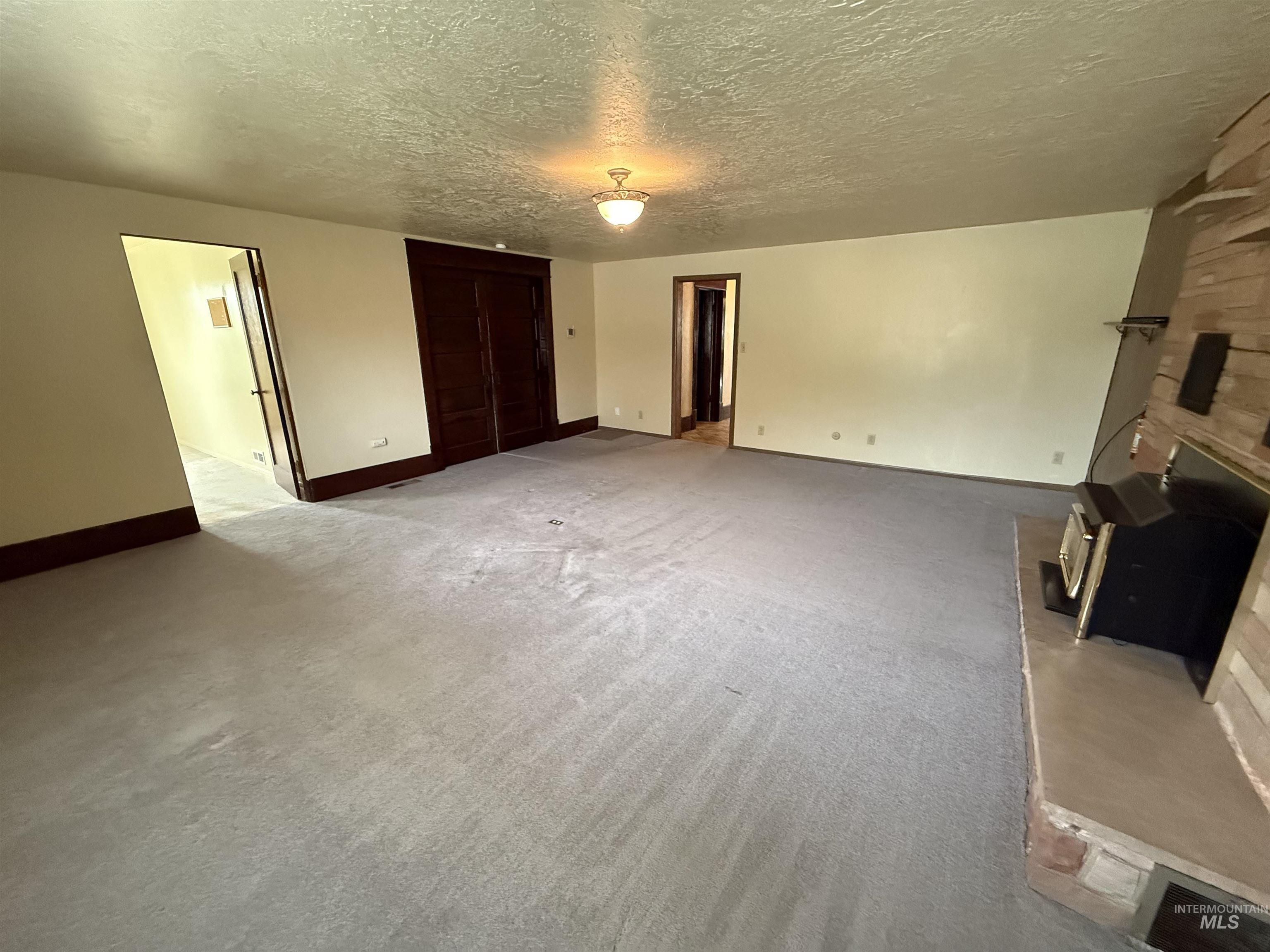 Unfurnished living room with a textured ceiling, carpet flooring, and a fireplace