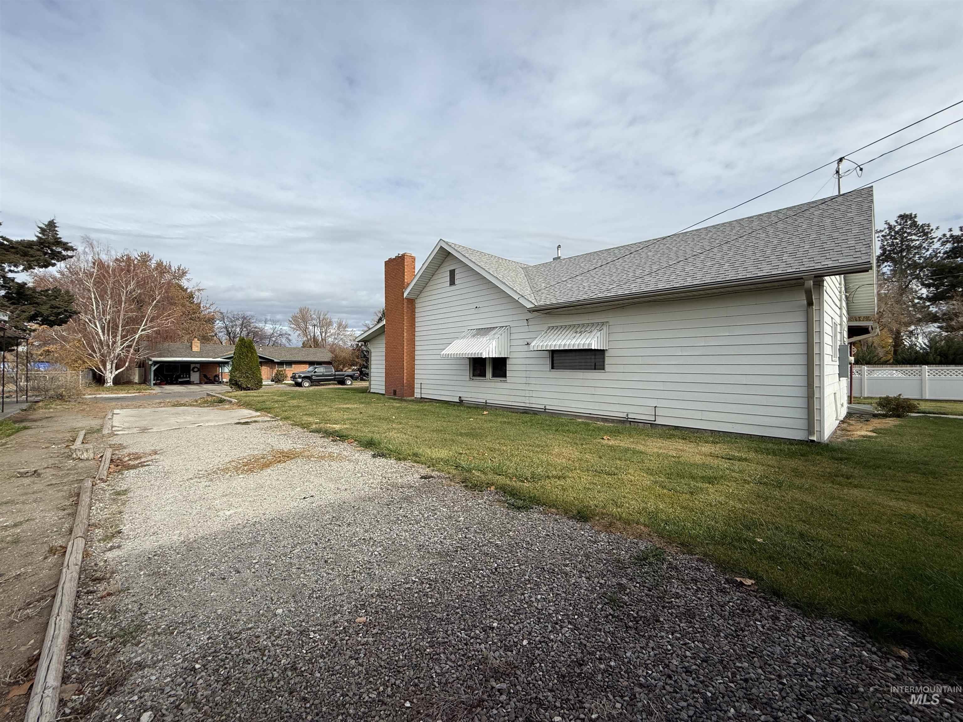 View of side of property with a shingled roof, driveway, and a chimney