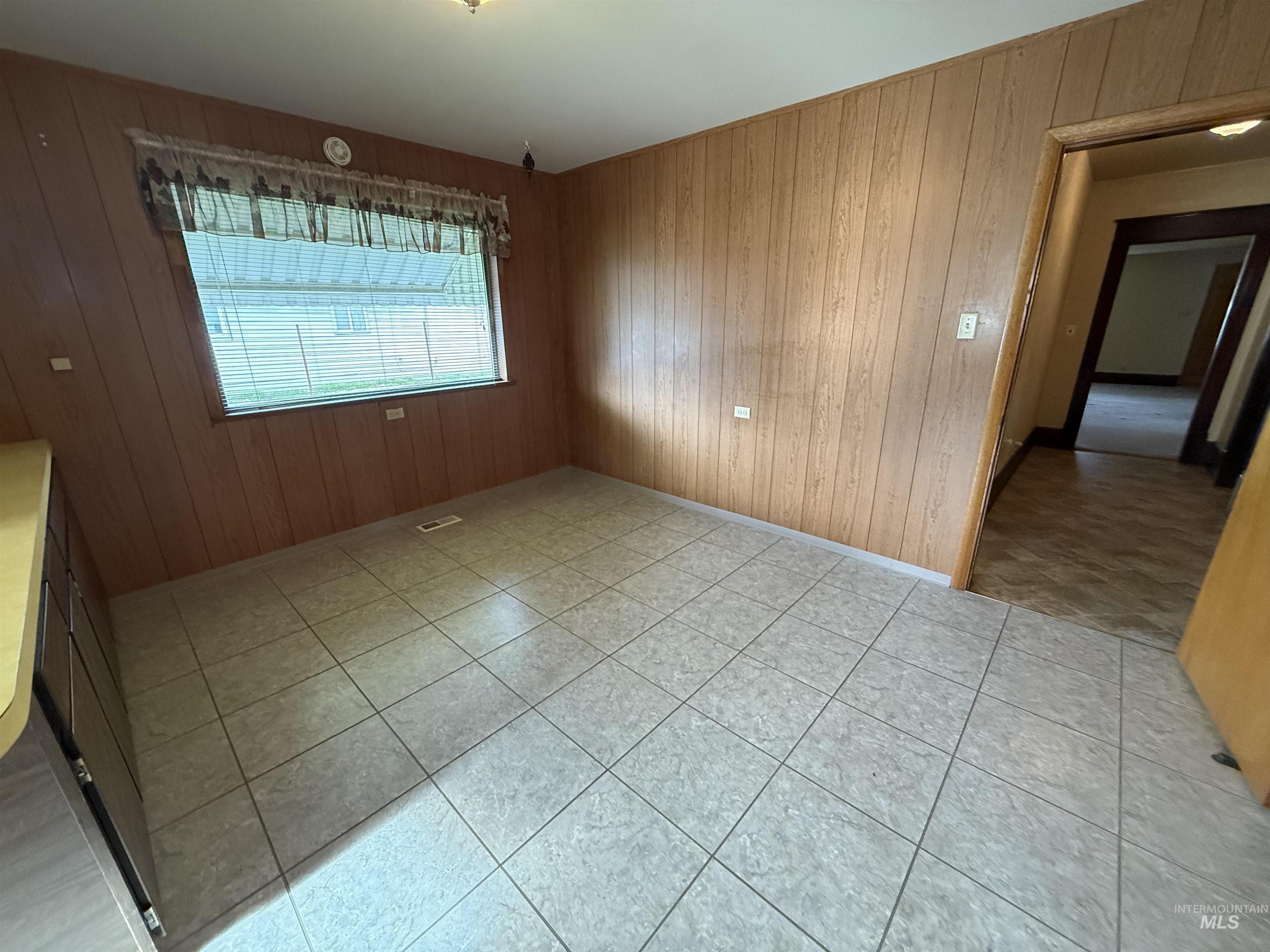 Unfurnished room featuring wooden walls and light tile patterned floors