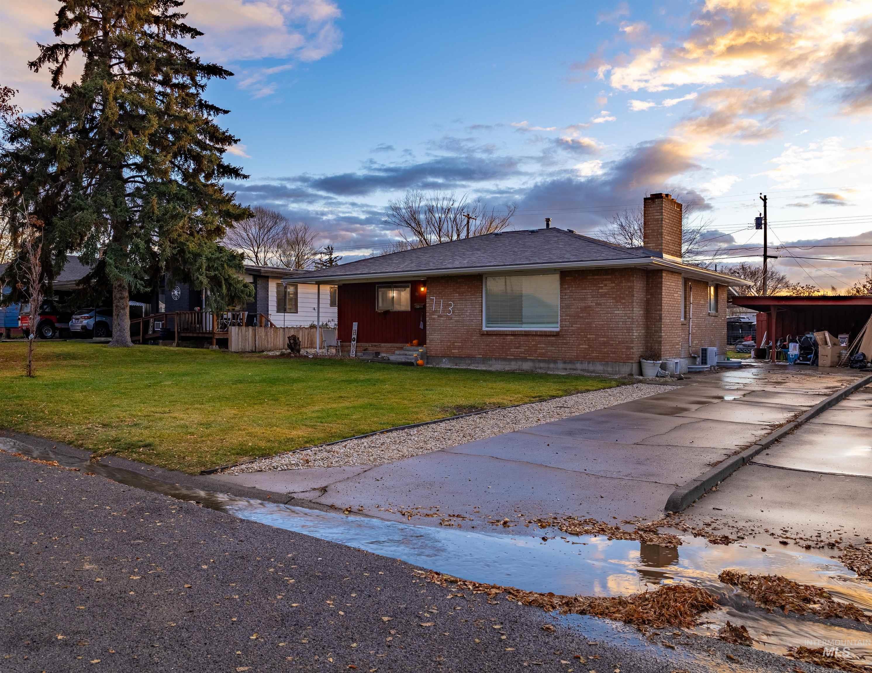View of front of house featuring brick siding, a front lawn, and a chimney