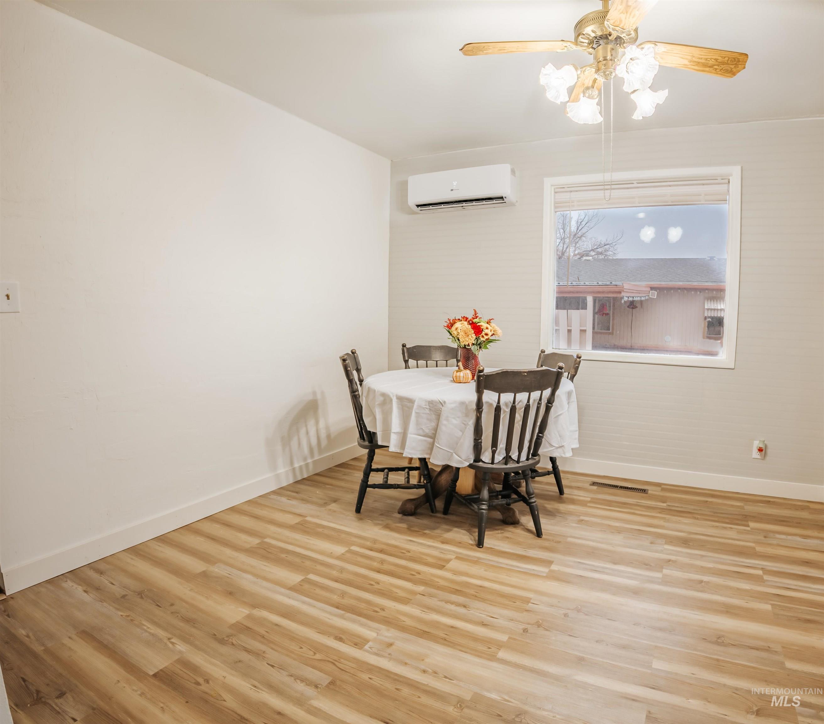 Dining area featuring wood finished floors, ceiling fan, and an AC wall unit