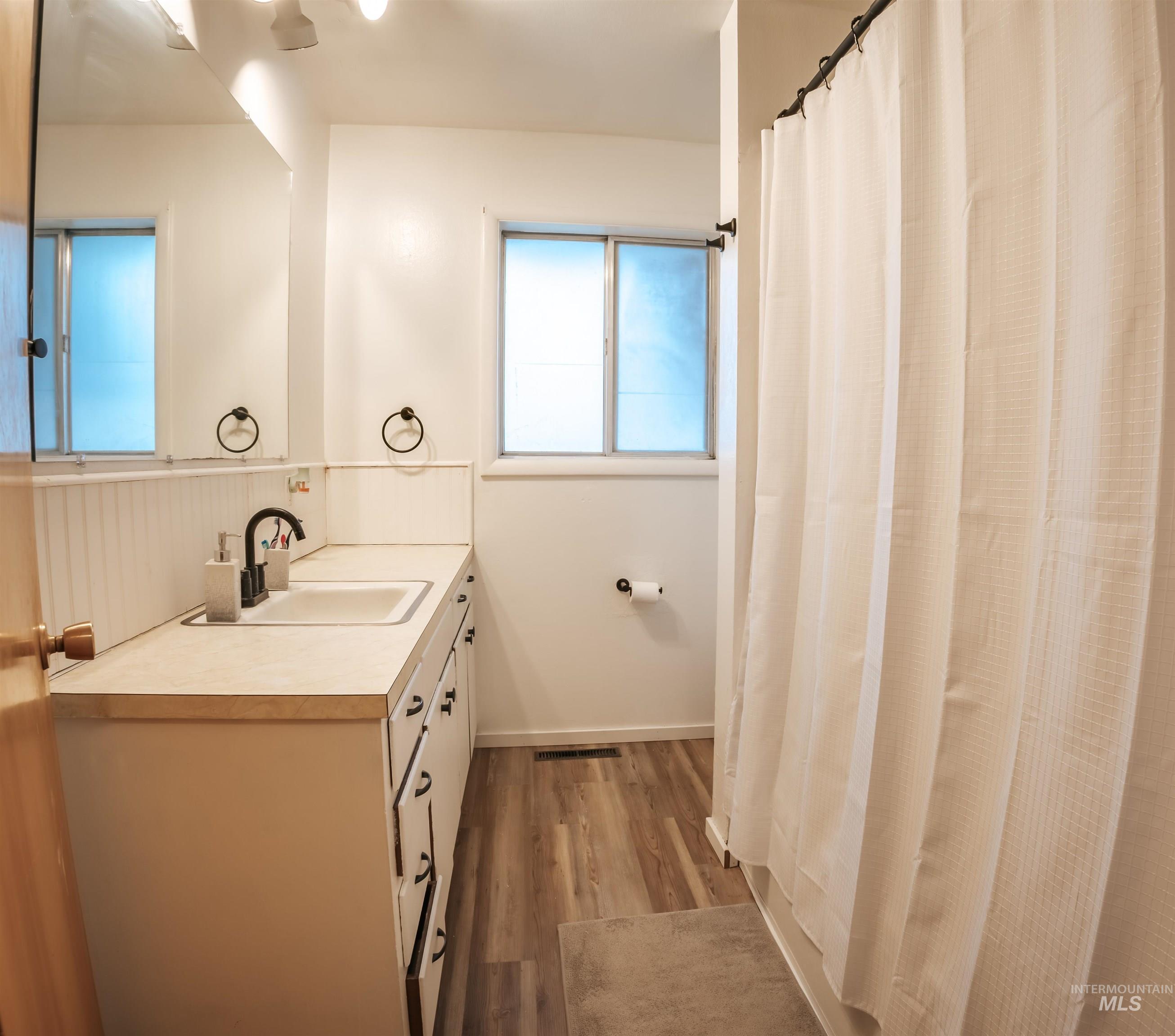 Bathroom featuring vanity, a shower with shower curtain, and light wood-style flooring