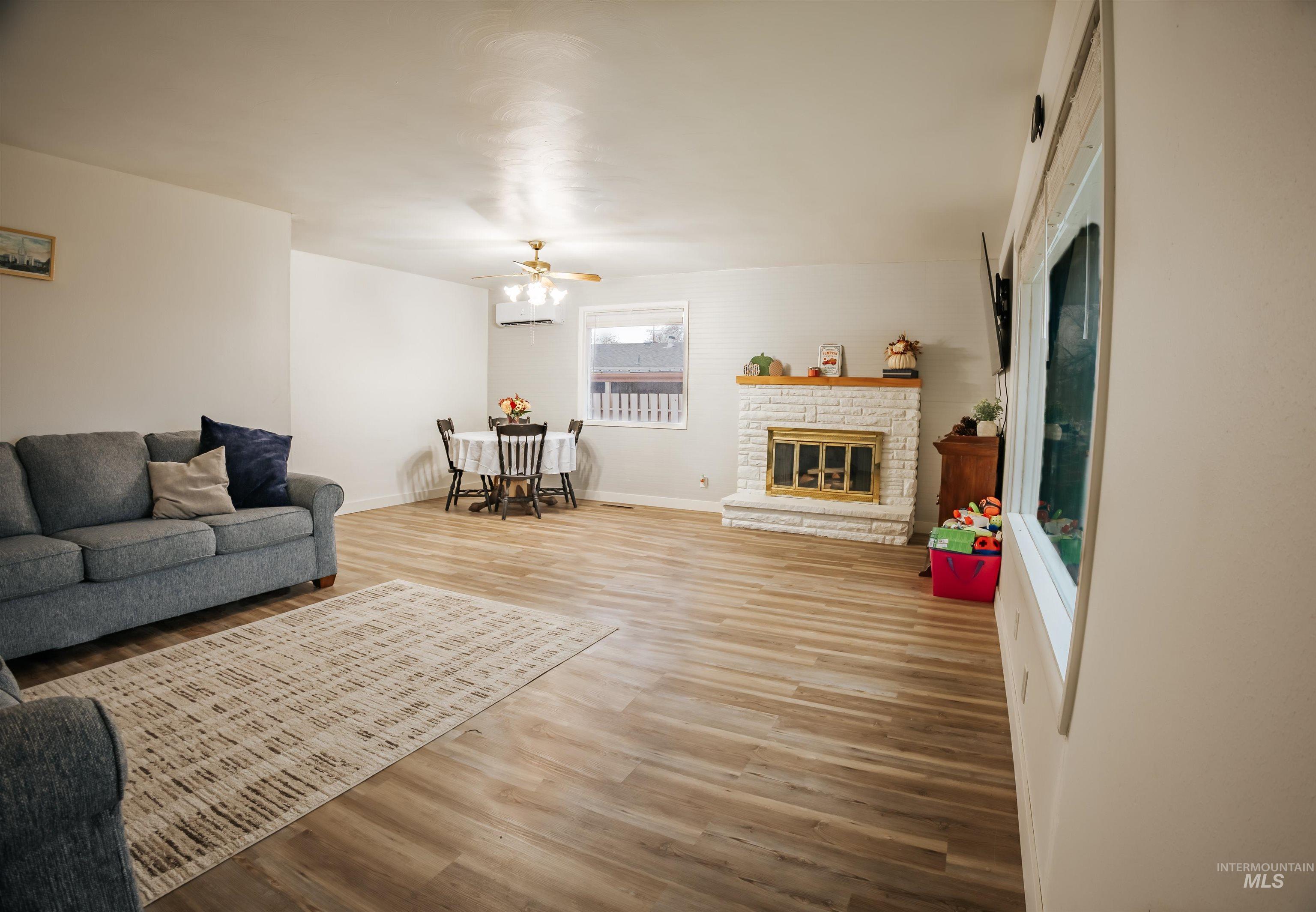 Living area with light wood-style floors, a glass covered fireplace, and ceiling fan