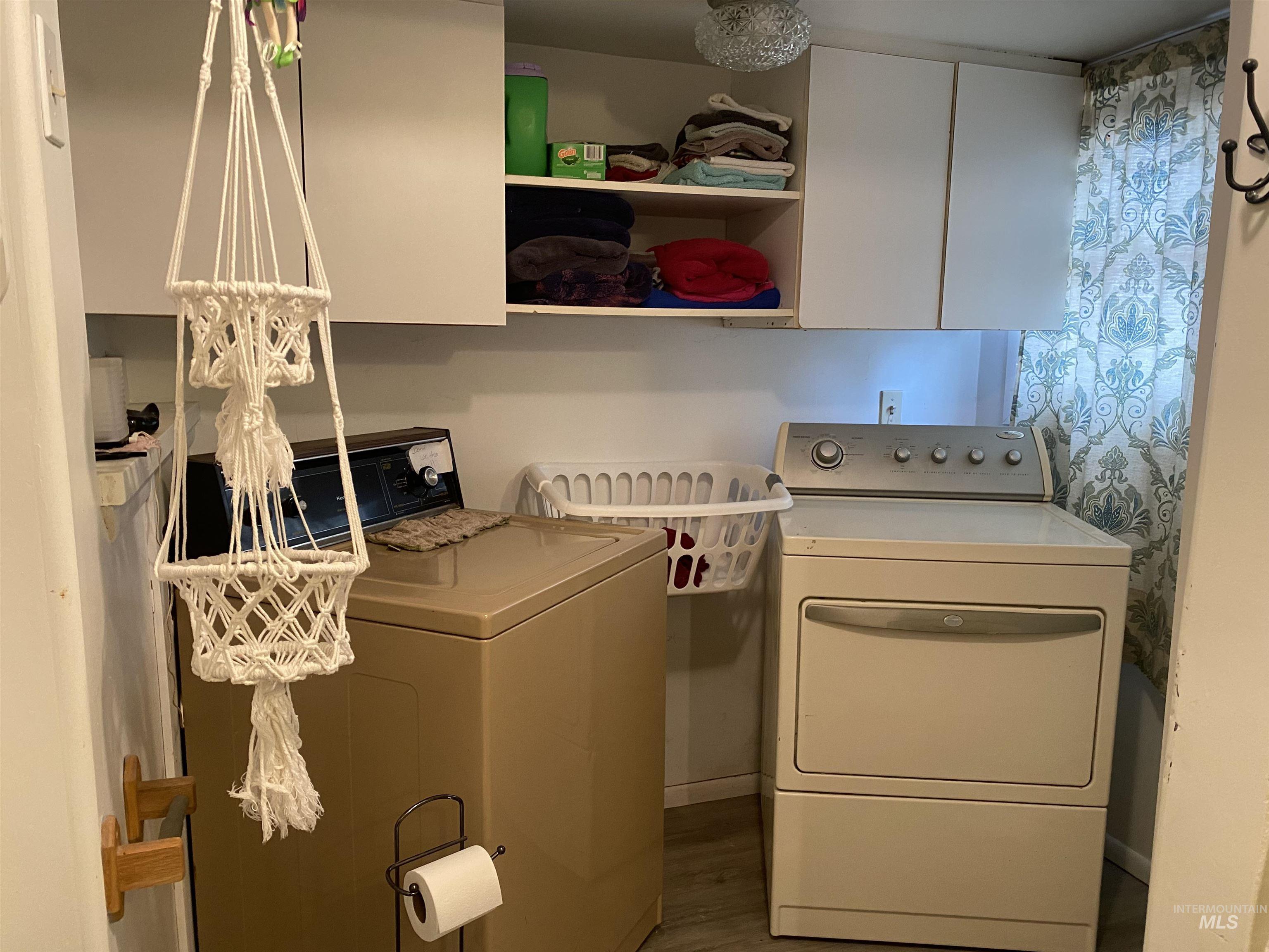 Laundry room featuring washing machine and dryer, wood finished floors, and cabinet space