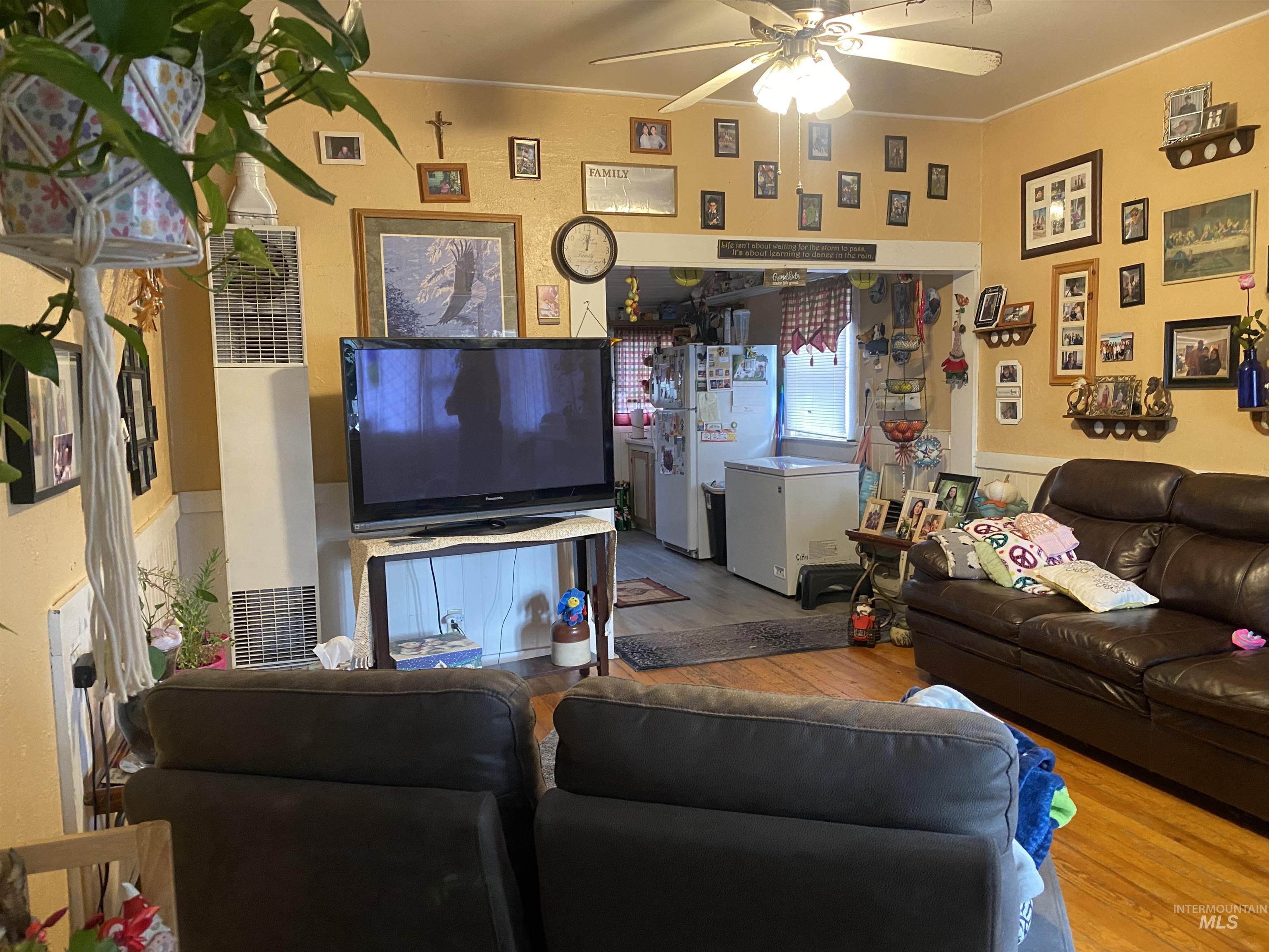 Living room featuring wood finished floors, a heating unit, and a ceiling fan