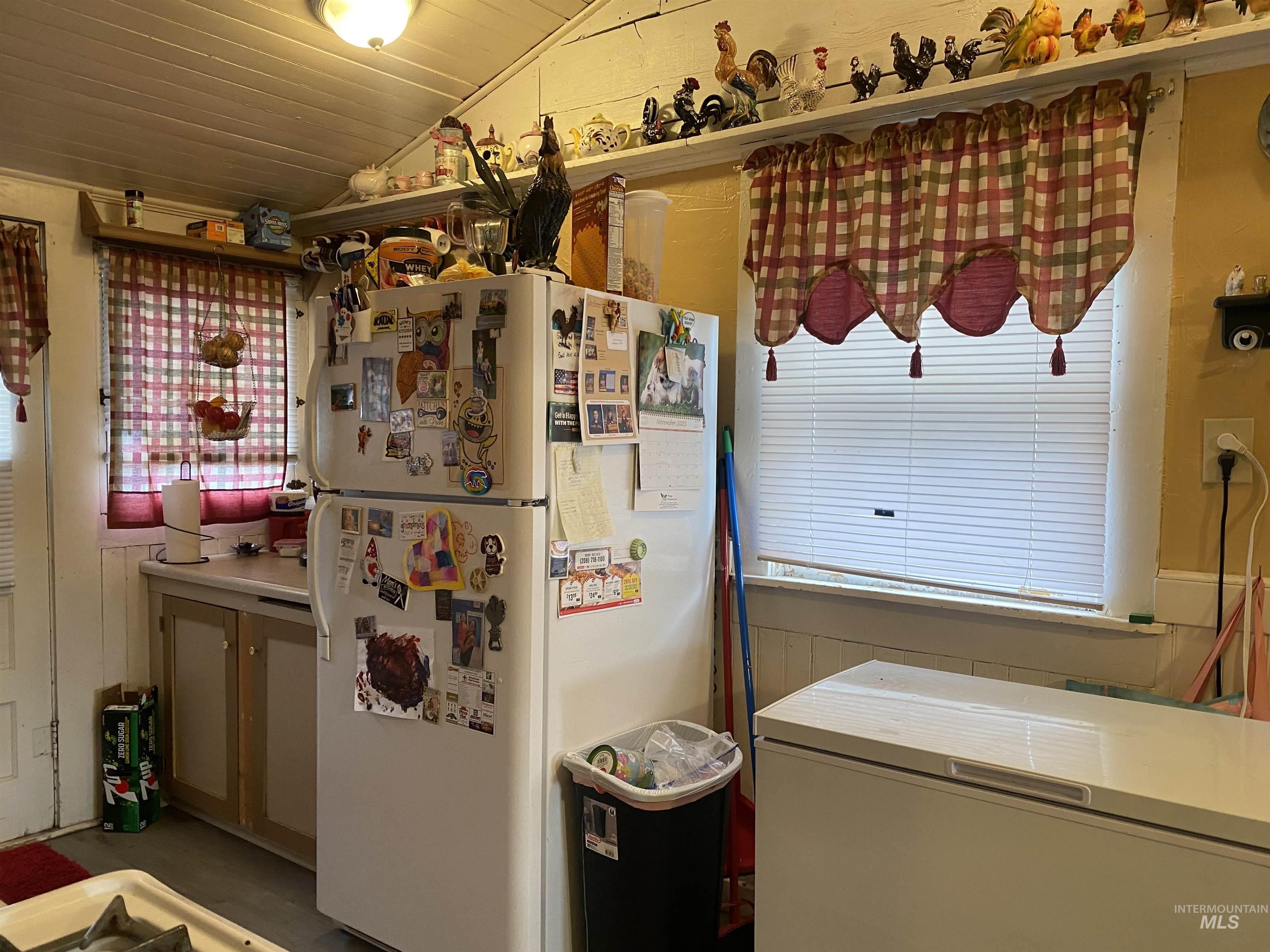 Kitchen featuring freestanding refrigerator, vaulted ceiling, healthy amount of natural light, and wooden ceiling