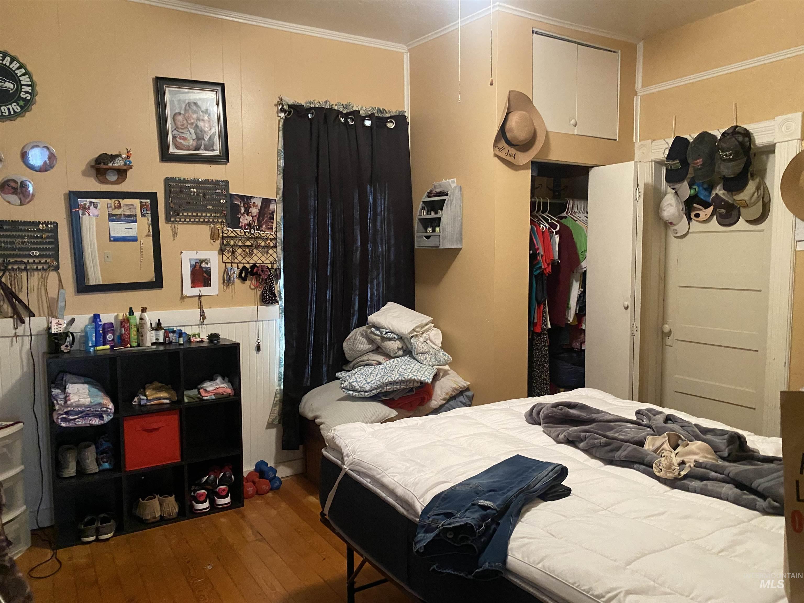 Bedroom with wood-type flooring, a closet, and crown molding