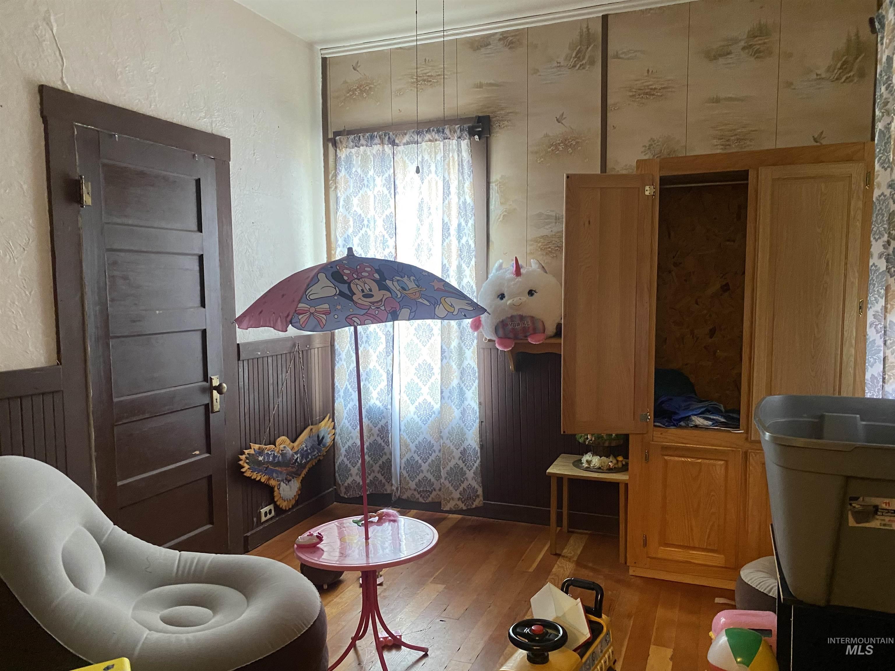 Living area featuring wood finished floors, radiator, a wainscoted wall, and a textured wall