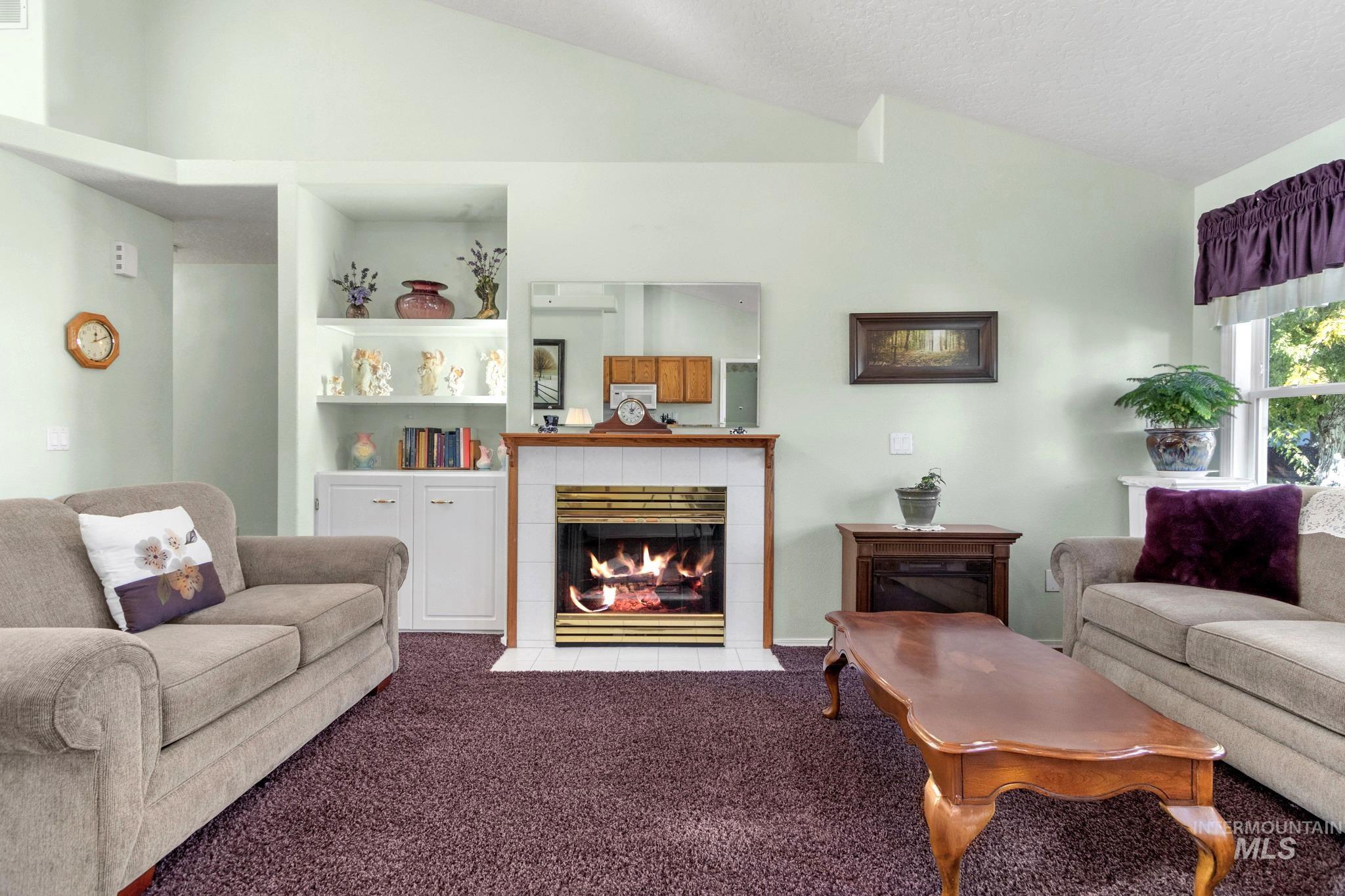Carpeted living area with a fireplace, a textured ceiling, and high vaulted ceiling